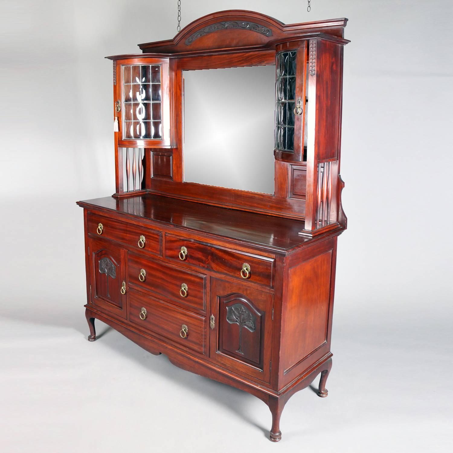 Antique Belgian court cupboard features walnut construction with mirrored back flaked by upper cabinets with bubble glass doors all above base with two drawers above two smaller central drawers flanked by cabinets with carved tree of life reserves,