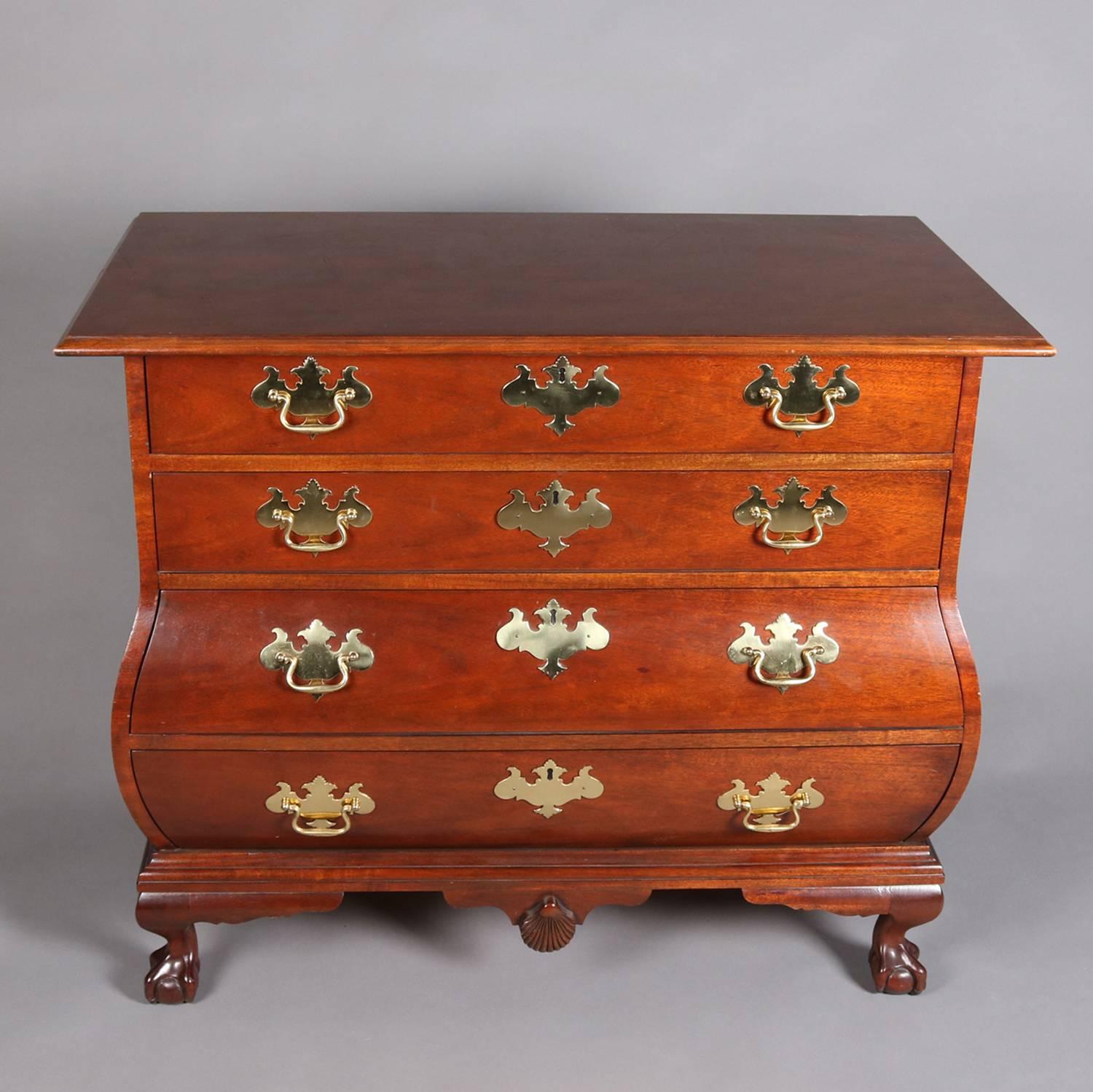 Historic Charleston Chippendale chest by Baker Furniture Company features mahogany construction with Bombe swell front form and having four drawers, skirt with central carved shell, and seated on claw and ball feet; original brasses included