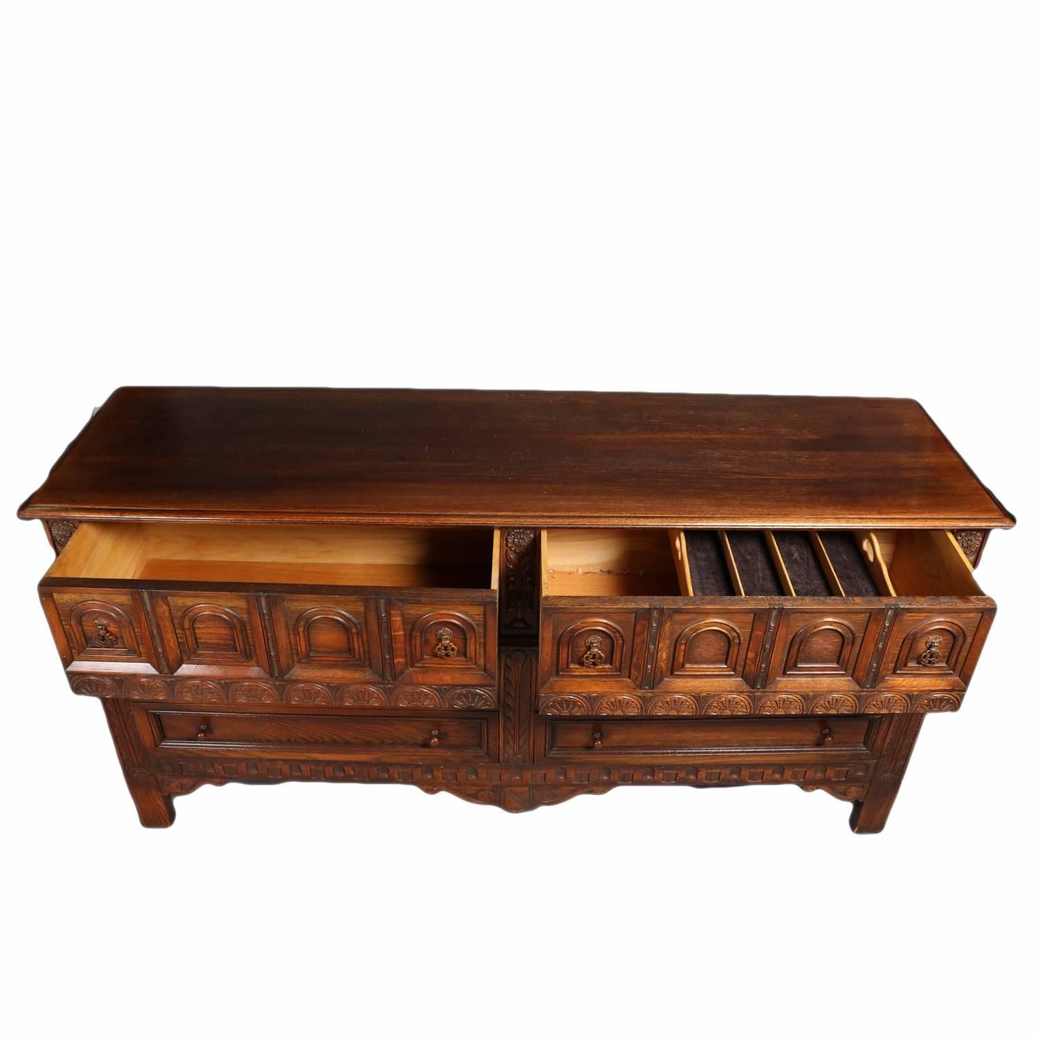 Antique Edwardian oak sideboard features Jacobean influence with heavily carved sunburst and foliate bordering, paneled sides and front including arched reserves in upper drawers, and scrolled skirting, en verso original Kittinger Furniture tag,