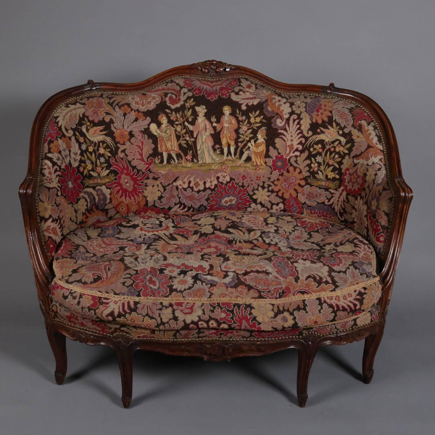 French Louis XV style settee features mahogany frame with carved foliate, floral and scroll decoration; upholstered in pictorial tapestry depicting courting scene in garden setting; 19th century.

Measures: 37