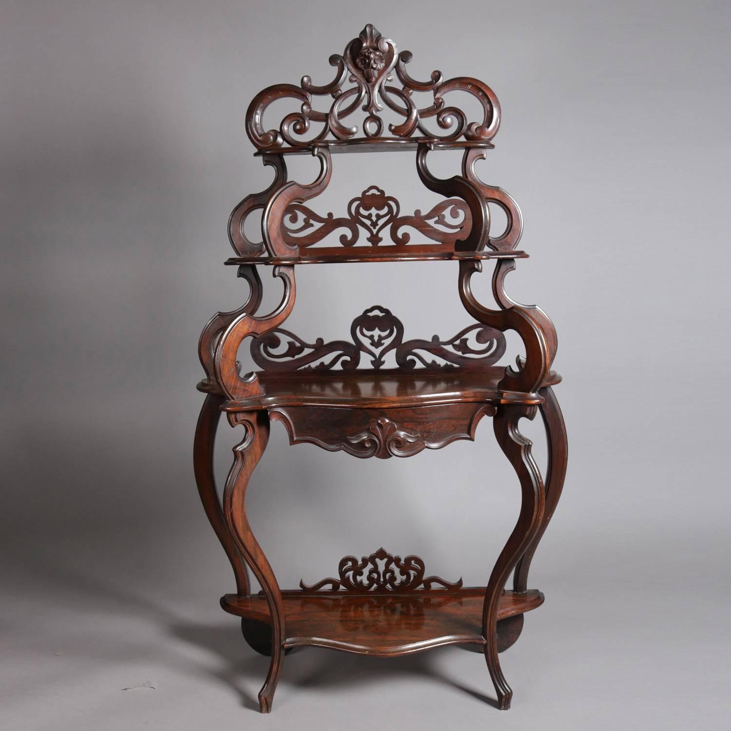 Antique Victorian Rococo carved rosewood etagere features four open display shelves, each with highly ornate carved and pierced foliate and scroll form backs and raised by s-scroll supports, 19th century.

Measures: 66