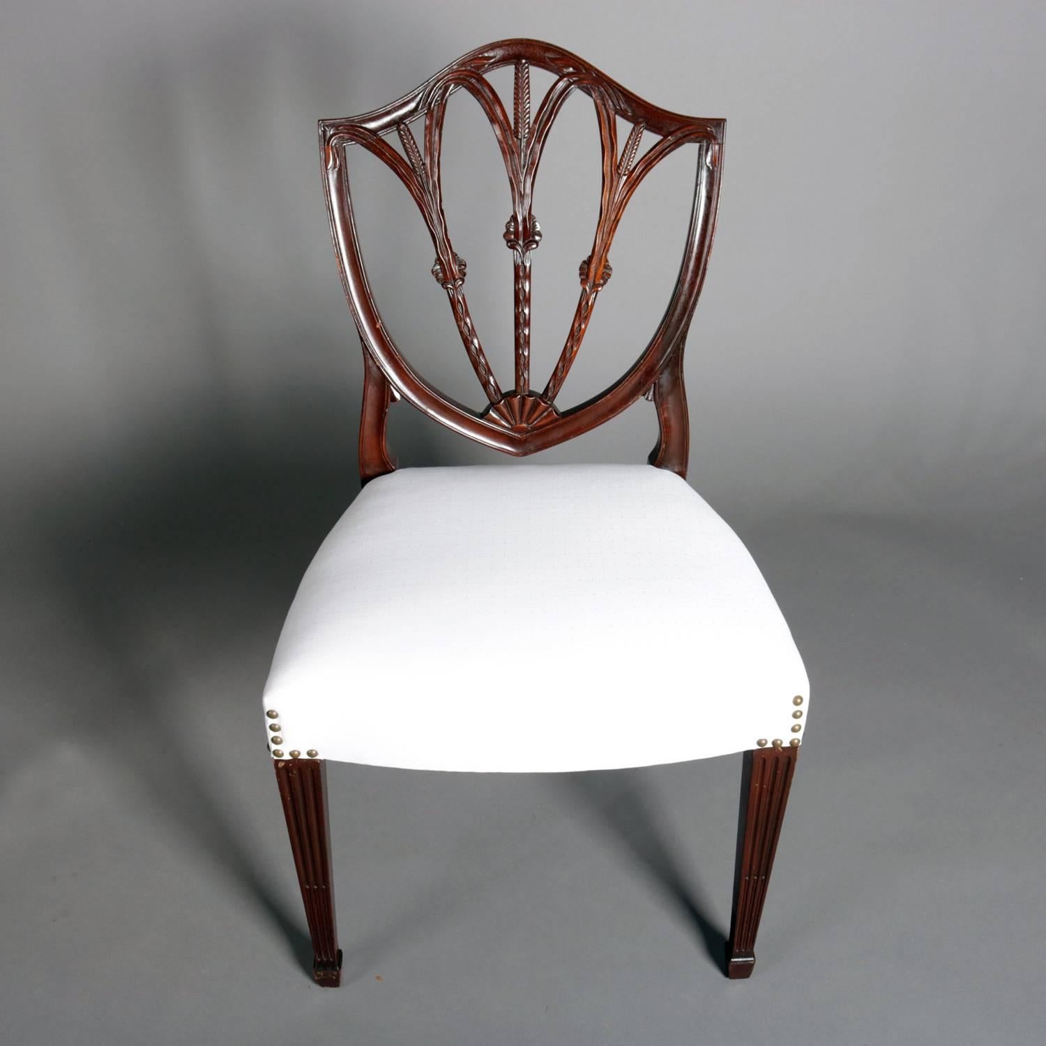 Set of seven Hepplewhite style mahogany shield back dining chairs feature carved wheat form slats and are seated on tapered legs terminating in spade feet, newly upholstered, one armchair and six side chairs, 20th century

Measure: 35.5