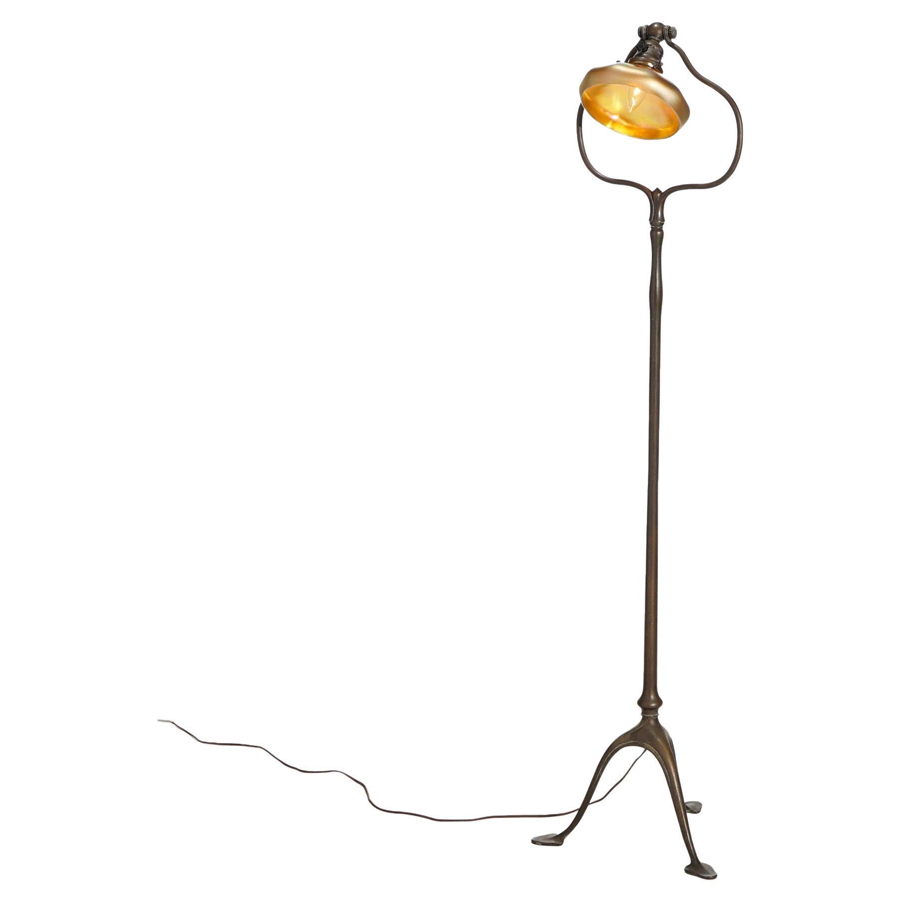 An antique Arts and Crafts floor lamp by Tiffany offers cast bronze tripod base with Tiffany Favrile gold aurene art glass shade, signed, c1920

Measures- 53'' H x 12'' W x 12'' D.

Catalogue Note: Ask about DISCOUNTED DELIVERY RATES available to