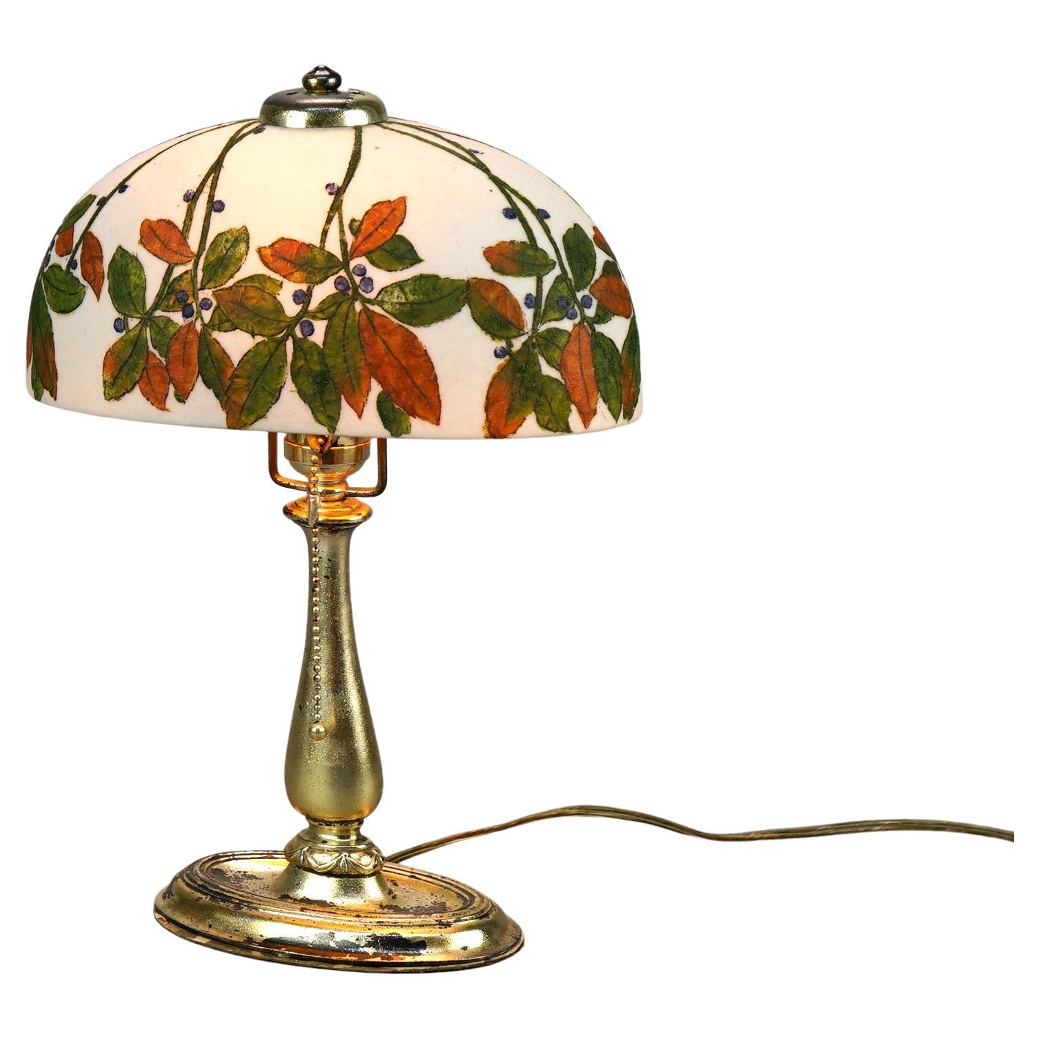 An antique boudoir lamp by Handel offers rare oval dome shade painted in leaf and berry design over single socket cast base with maker label as photographed, c1920

Measures- 14''H x 10''W x 5''D.