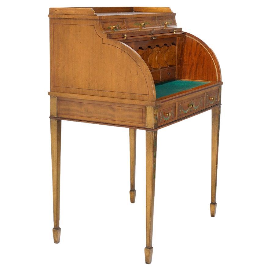 An antique Adam decorated ladies desk offers satinwood construction with roll top opening to interior with storage compartments and pull-out writing surface, over three drawers, raised on square and tapered legs, hand painted foliate elements