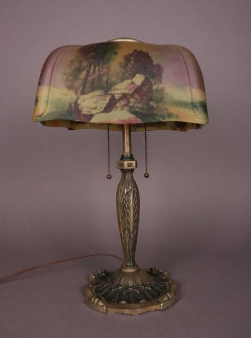 Antique Pittsburgh obverse/reverse painted table lamp features bronze base and vibrant landscape scene with pleated ends, circa 1920.