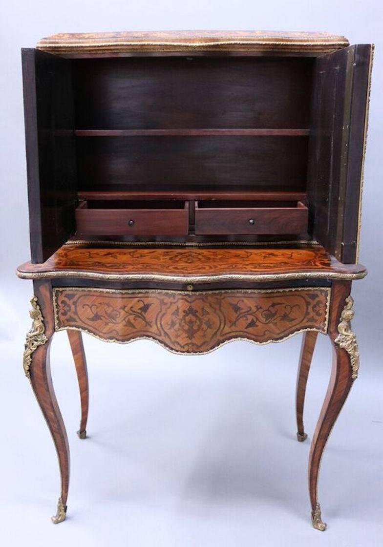Elegant French mahogany bonheur du jour ladies desk features curvilinear design accented with traditional Louis XIV gold gilt ormolu, detailed rosewood and satinwood marquetry, and Sèrves porcelain plaques with hand-painted scenes. The image edge