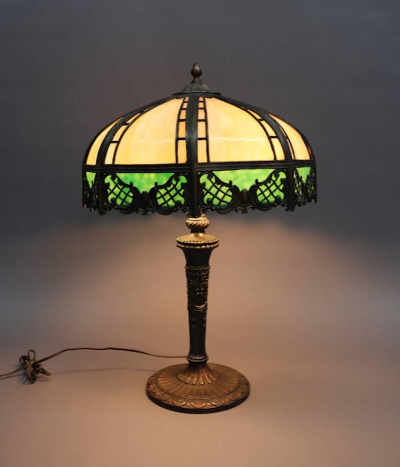 Bronzed metal lamp features slag glass shade in brown, green and red tones, circa 1920. The lamp has two independently controlled bulbs. Fine craftsmanship throughout.

