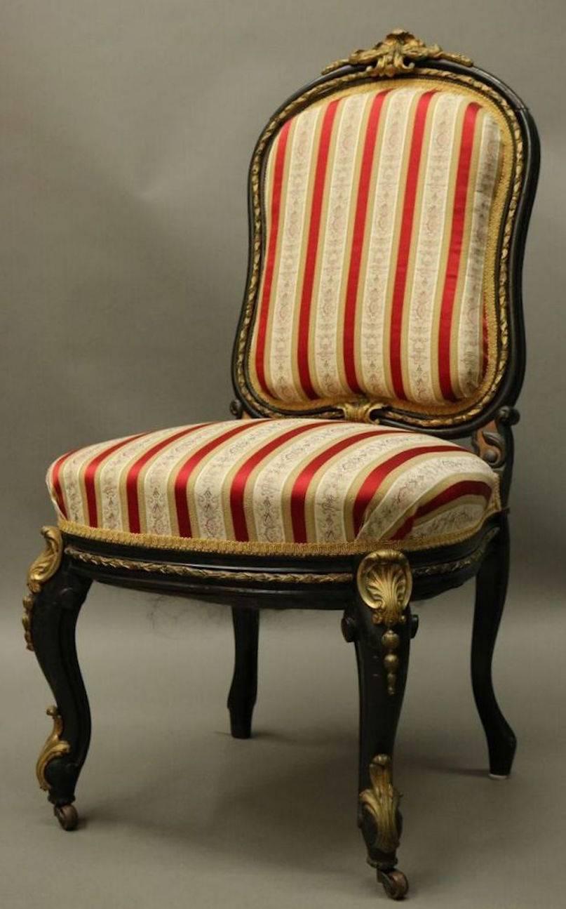 Four antique Louis XIV style side chairs feature ebonized frame, bronze ormolu trim and rich red and white striped upholstery, circa 1880 (more recent upholstery).