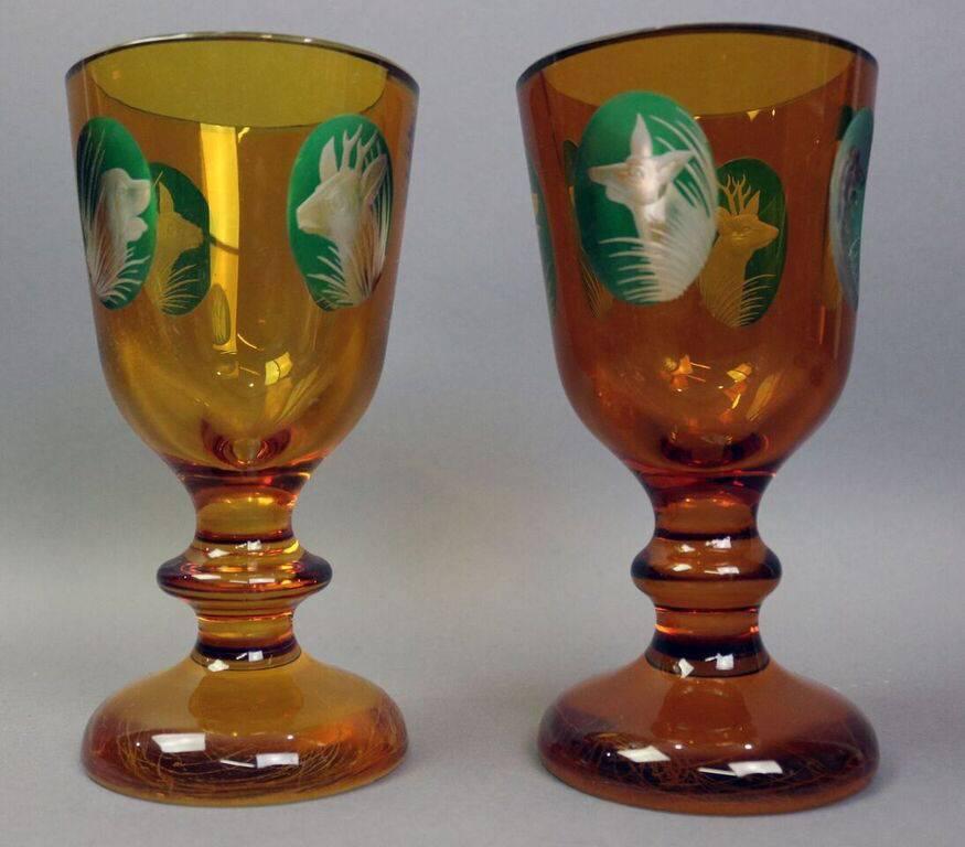 Set of 12 early amber bohemian hunt glasses feature cameo cut figures of deer, hunting dogs (dachshund and spaniel) and fox against green ground, circa 1850.