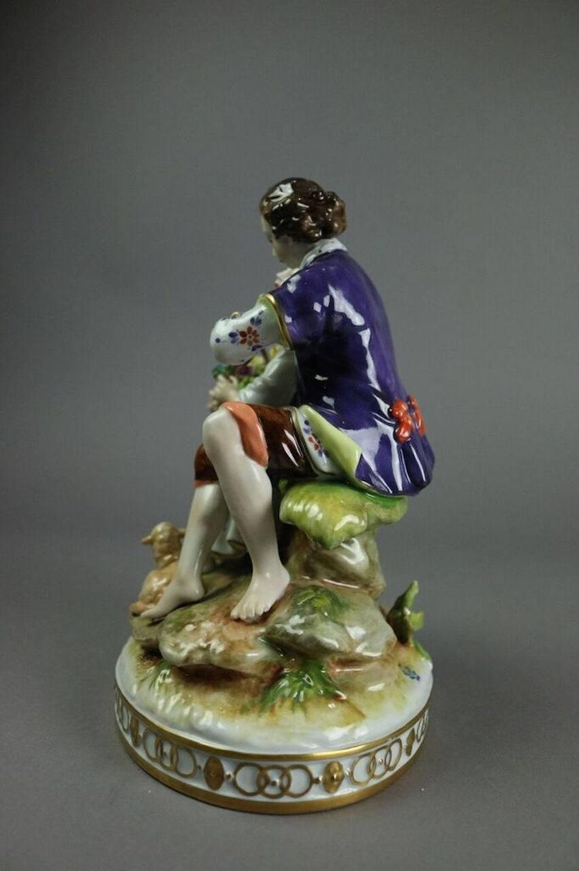 Volkstedt Meissen style porcelain figurine features hand-painted courting couple and is stamped on topside of base with blue mark and date of 1762. The Volkstedt porcelain marks began to appear in the latter third of the 18th century in the