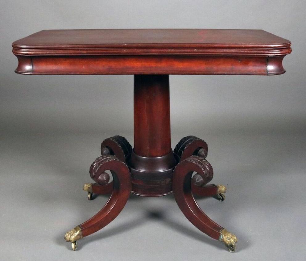 Federal style game table reminiscent of the Duncan Phyfe school features mahogany construction with carved scrolled acanthus leaf legs terminating in bronze mounts with casters, circa 1820.
Top measures closed 35" x 18" and open 35"