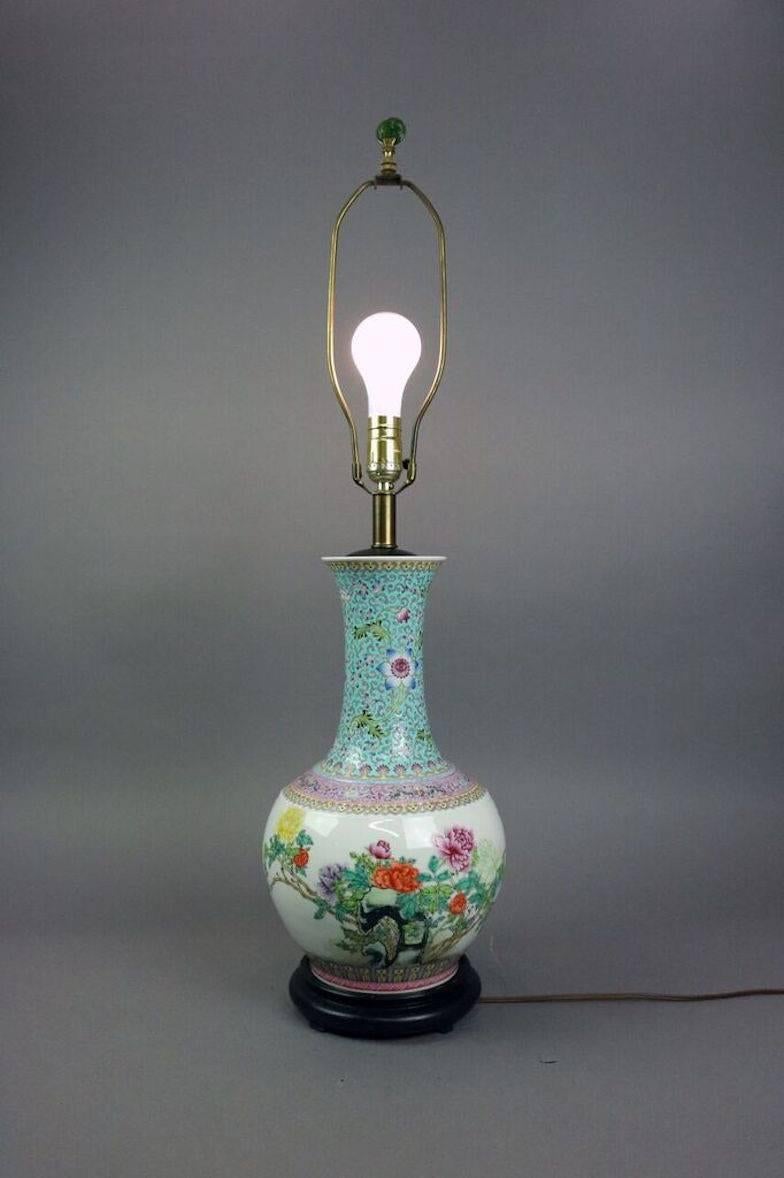 Antique Qianlong hand enameled polychrome Chinese Famille Verte floral decorated lamp features peonies with chop marks en verso atop carved rosewood base, 19th century.

34" height with harp x 9" diameter.