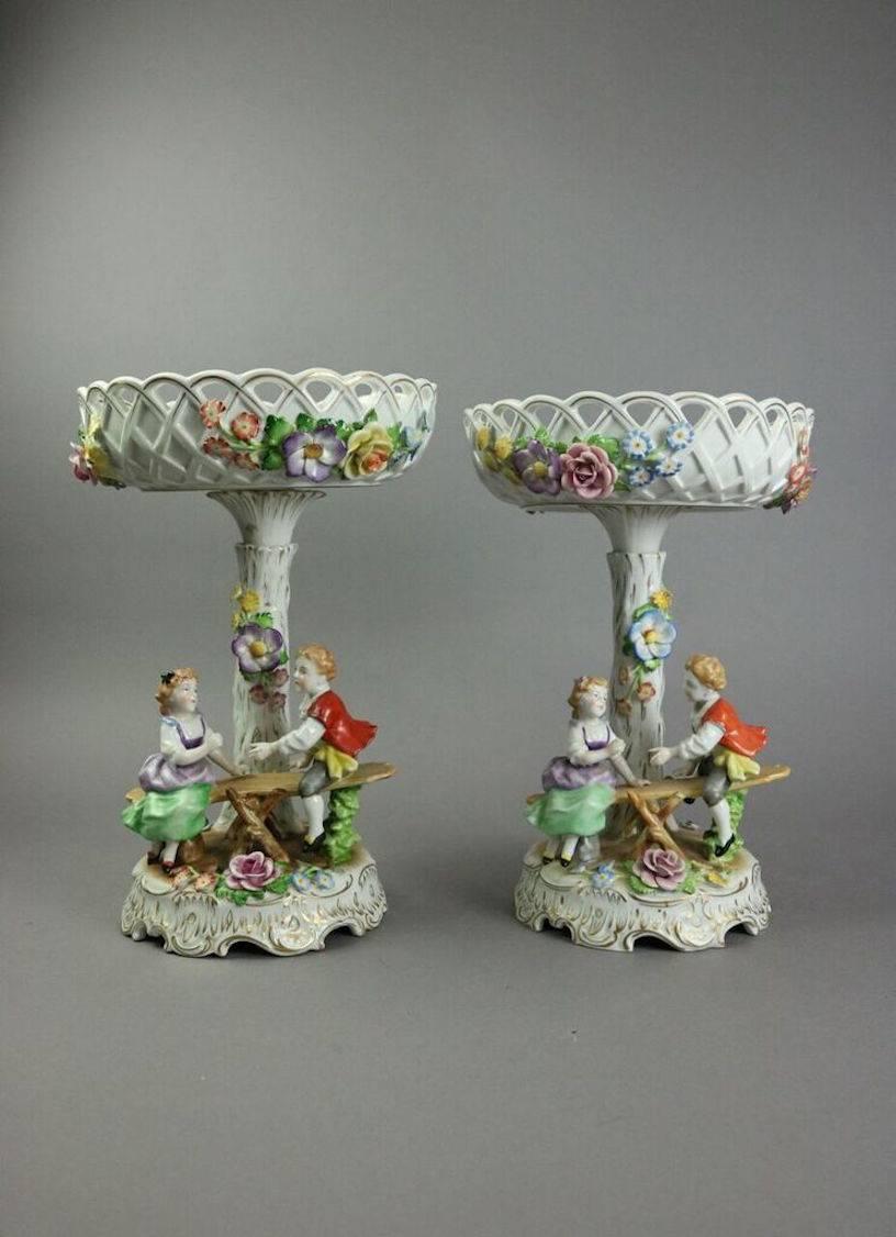 Antique pair of German Von Schierholz hand-painted porcelain figural compotes with young girl and boy on seesaw, stamped with green crown and shield mark on base, late 19th Century