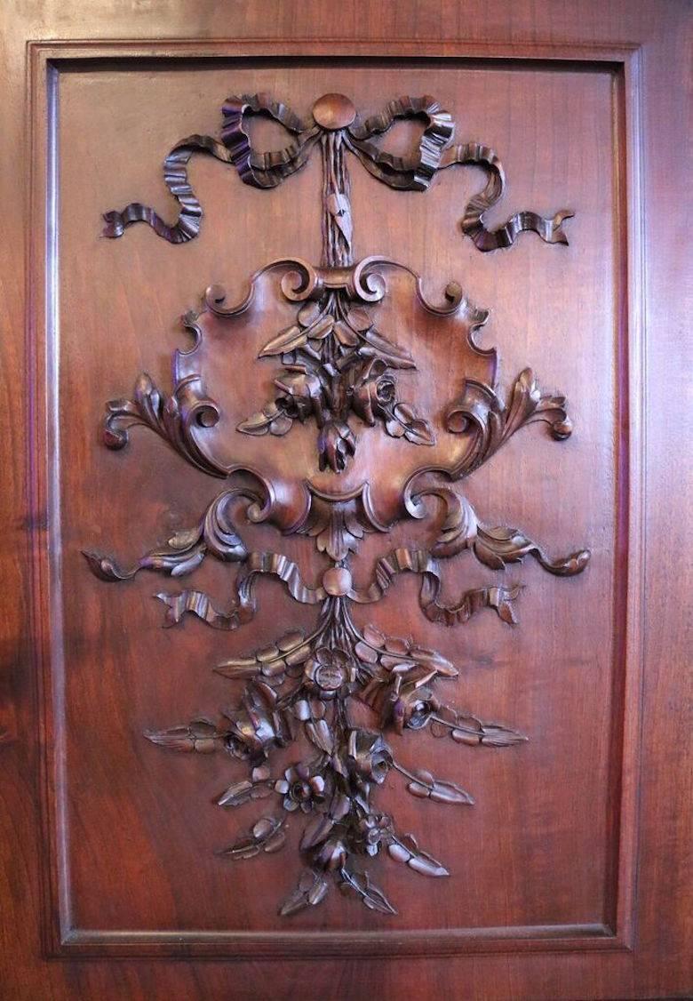 Antique English Henry II walnut court cupboard features prominently carved pierced foliate crest and finials above floral carved center panel door flanked by eight-panel beveled glass galleries and turned and reeded column supports. The base