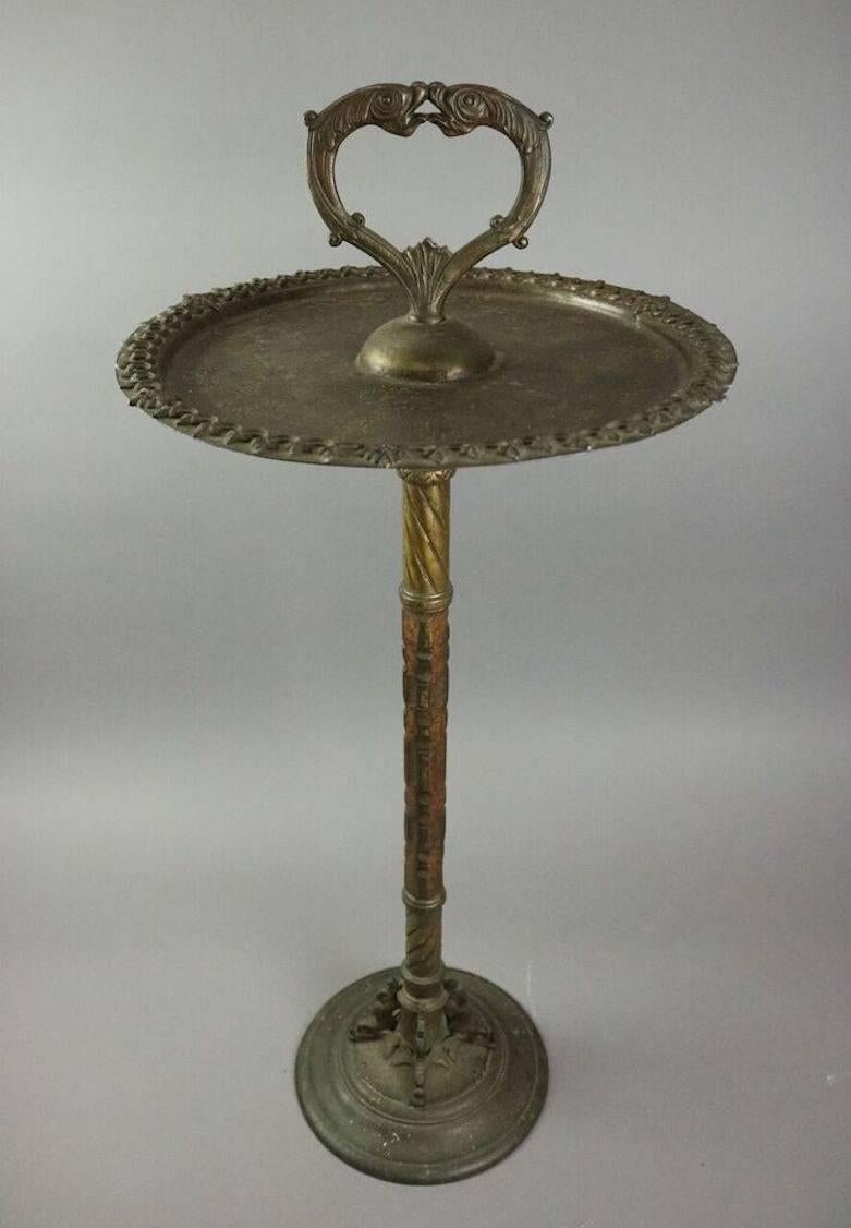 Antique Oscar Bach, Segar Studios cast bronze smoking stand features dolphin base rising to ash receptacle (ashtray) topped with finial of facing dolphins, imprinted on underside of base The Segar Studios, New York, measures: 33.5" H, circa