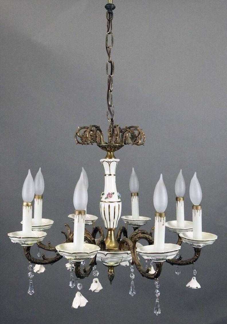 Antique eight-light chandelier features brass hardware and arms with C-scrolls and foliate motif, porcelain body highlighted with hand-painted roses and gold accents, porcelain bobeches and inverted roses, and crystal prisms, re-wired, circa