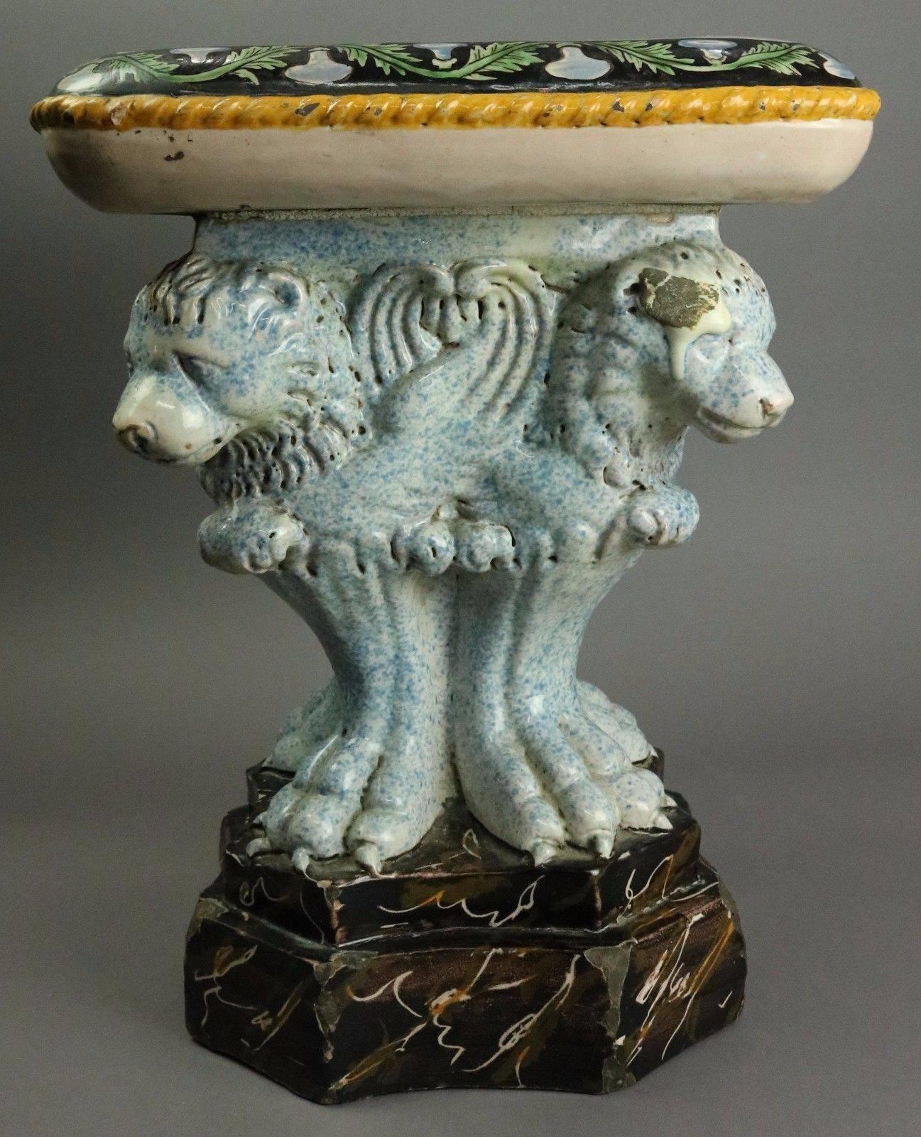 Antique Italian Majolica pottery figural garden seat features a plinth of lions on faux marble painted base rising to the seat with hand painted scene of cherubs and mythical goat inside a garland surround with twisted rope eddging. 

Measurements -