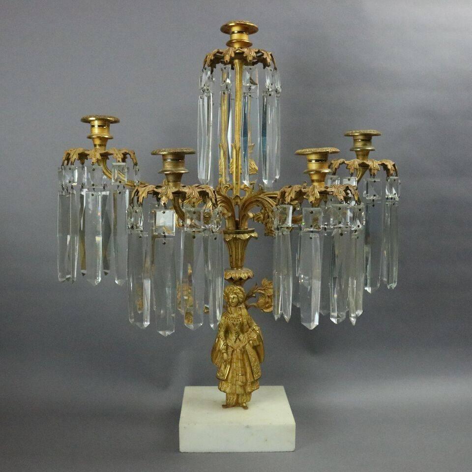 Set of three French figural gilt bronze mantel candelabra feature bobeches of acanthus leaves and foliate arms decorated with cut crystal prisms and Moorish maiden in native ceremonial garb atop a marble base, central with five lights and flanking