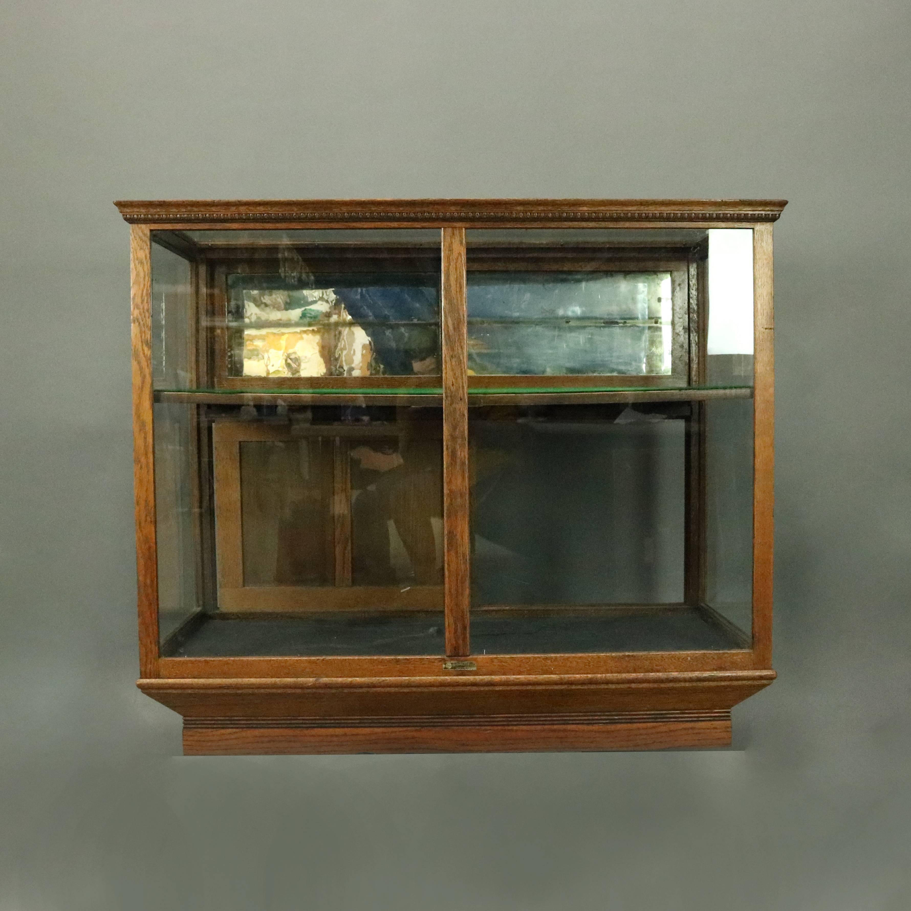 Antique country store mercantile display showcase by Waddell W. W. Works, Greenfield, Ohio, features oak construction with egg and dart trim, two sets of sliding doors reveal shelved mirror-back interior, circa 1890.

Measures: 38" H x