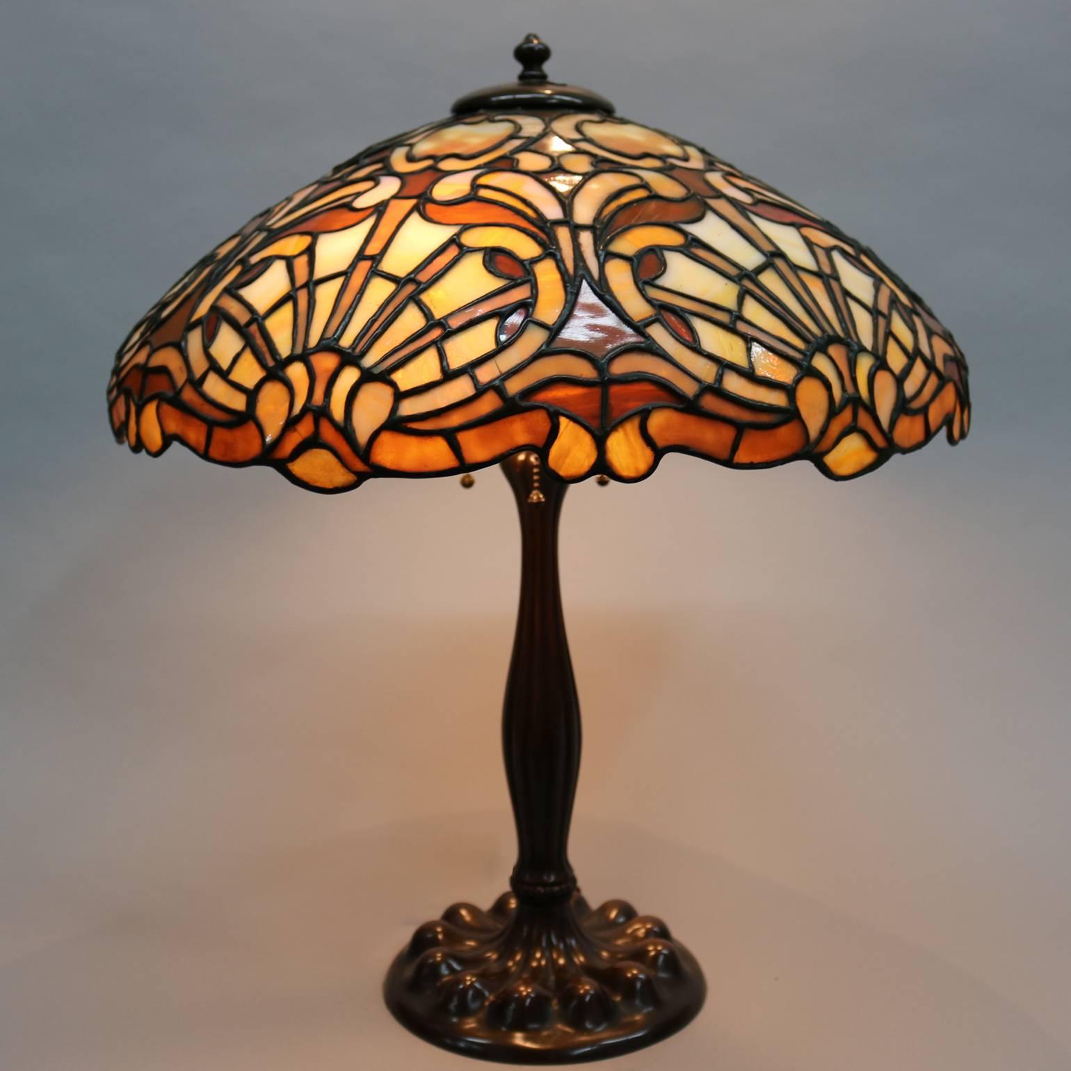 Antique Duffner and Kimberly Art Nouveau mosaic leaded stained glass lamp features a dome shade with caramel shell design, the standard with reeded hour glass form rising to support a two-socket cluster, circa 1911

Measures: 24
