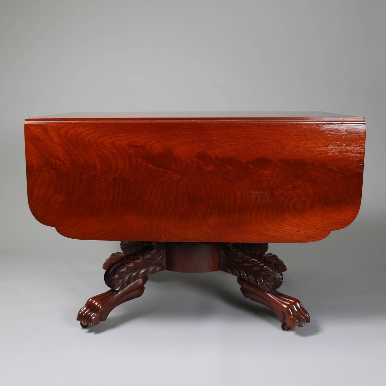 Antique American Empire flame mahogany pedestal table features carved claw feet with acanthus decorated legs and scalloped drop-leaf top, circa 1850

Measures: 28.5" H x 42" D x 23.5" W closed, 53.5" W open.