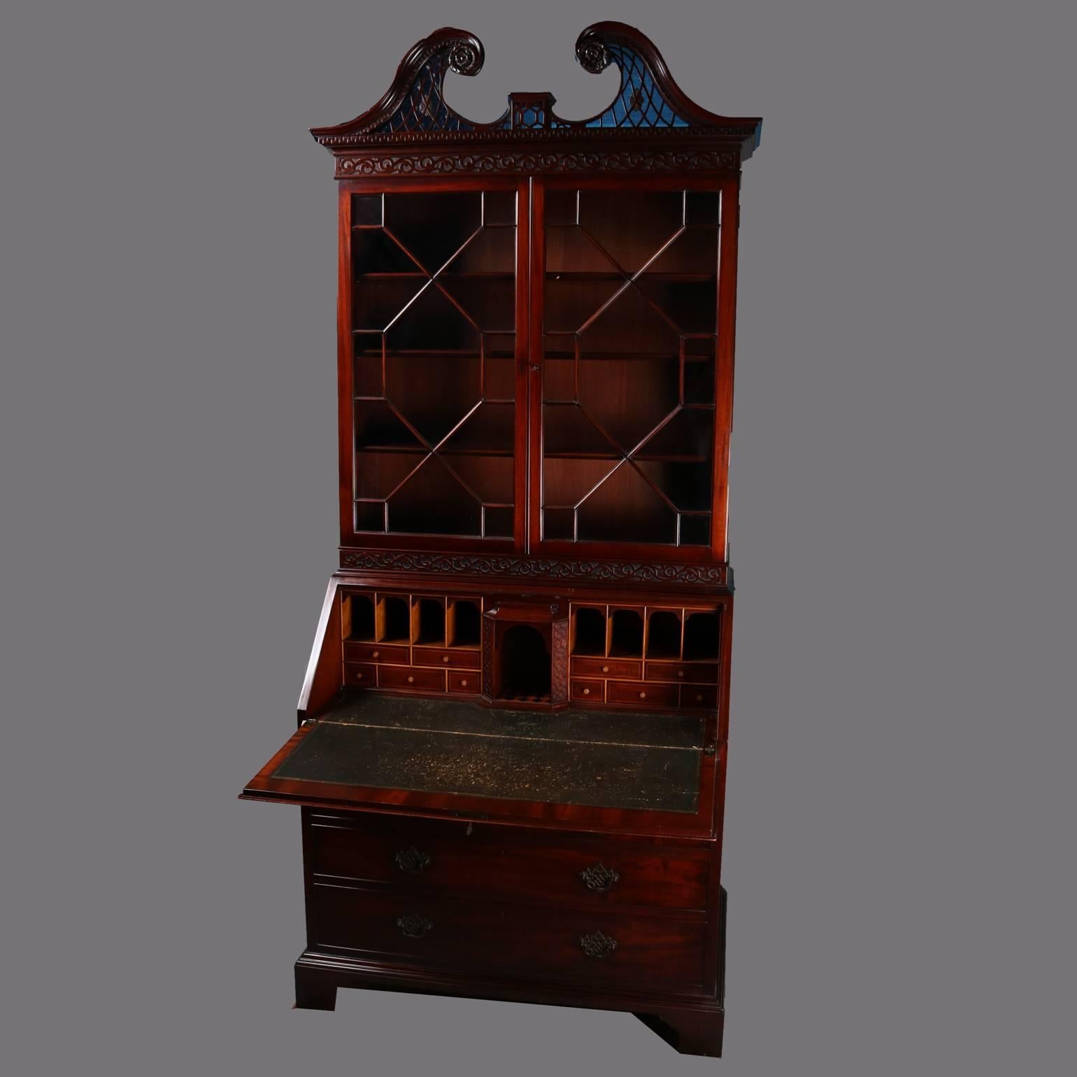 Antique Federal mahogany secretary features the top section a double glass door cabinet bookcase topped with broken-arch filigree pediment and two pull-out candle stands; the base section a slant-top desk opening to leather writing surface with