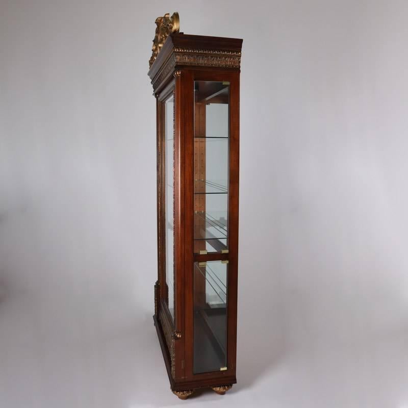Pair of mahogany curio cabinets by Pulaski Furniture feature foliate carved case with flaking columns and pierced giltwood foliate crest, bevelled glass doors opening to mirror back and lighted shelved display, 20th century.

Measure: 92" H x