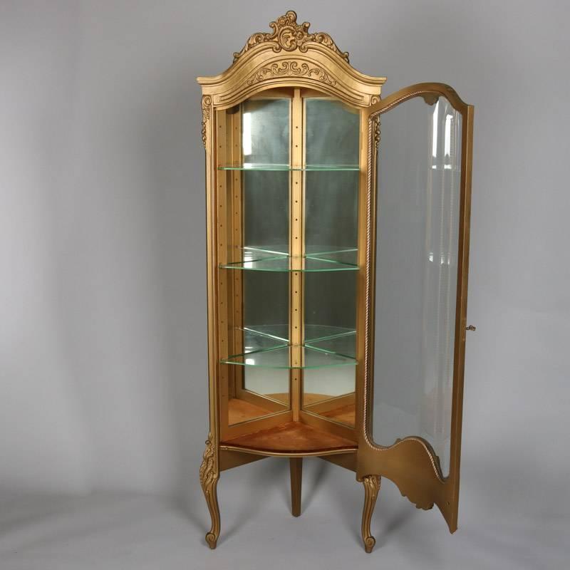 French Louis XVI giltwood petite corner vitrine features foliate, scroll and floral decoration, locking door opens to mirror back display with adjustable glass shelves, 20th century

Measures: 70" H x 23" W x 17" D.