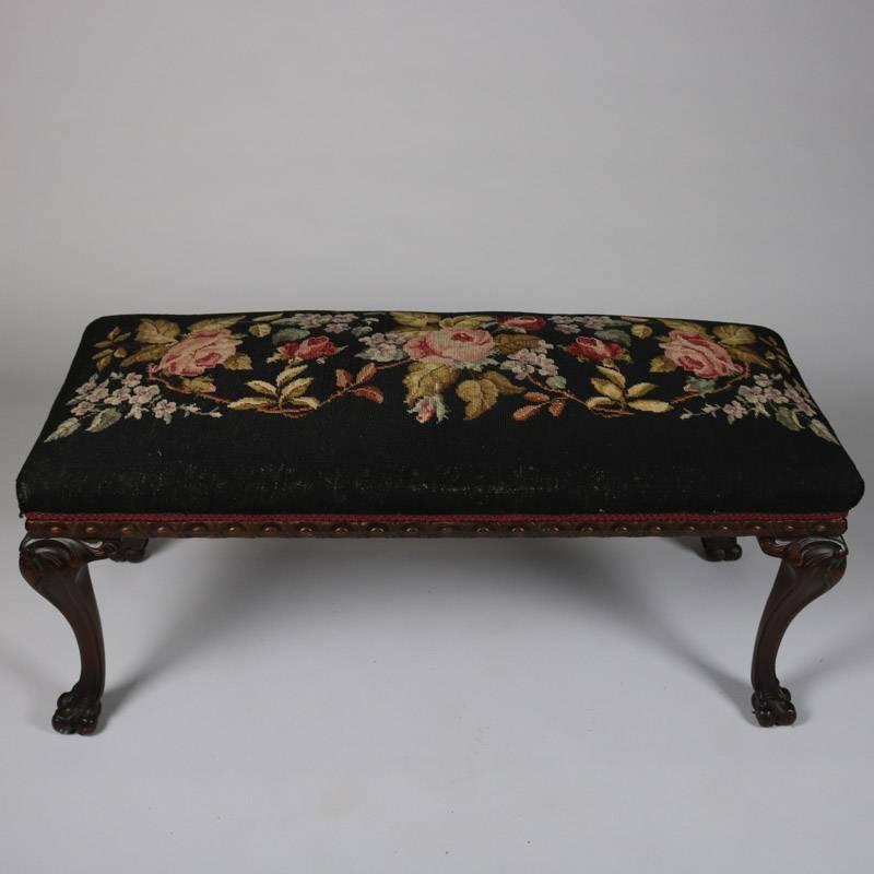 Antique Chippendale bench features carved mahogany frame with paw feet and floral needlepoint cushion, 19th century

Measures: 19" H x 45" W x 18" D.