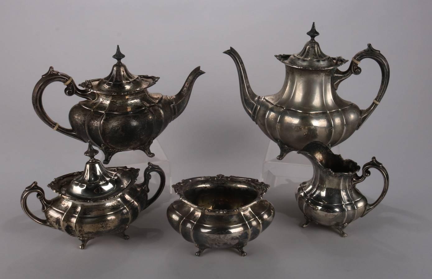 Antique sterling silver Hampton Court five-piece tea set by Reed and Barton features footed and faceted form with scrolled handles; set includes tea pot, coffee pot, covered sugar, creamer and waste bowl; hallmark 