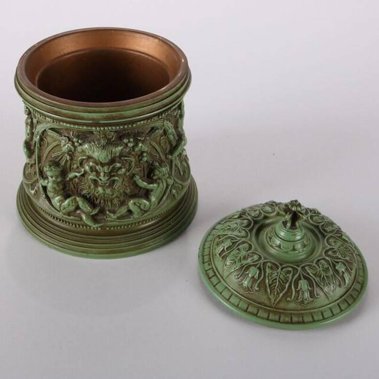 Antique Classical verdigris enameled white metal lidded humidor features wind god and cherubs with internal copper lining

Measures - 6.5" H x 4.75" bs, interior: 3" x 3.25" D.