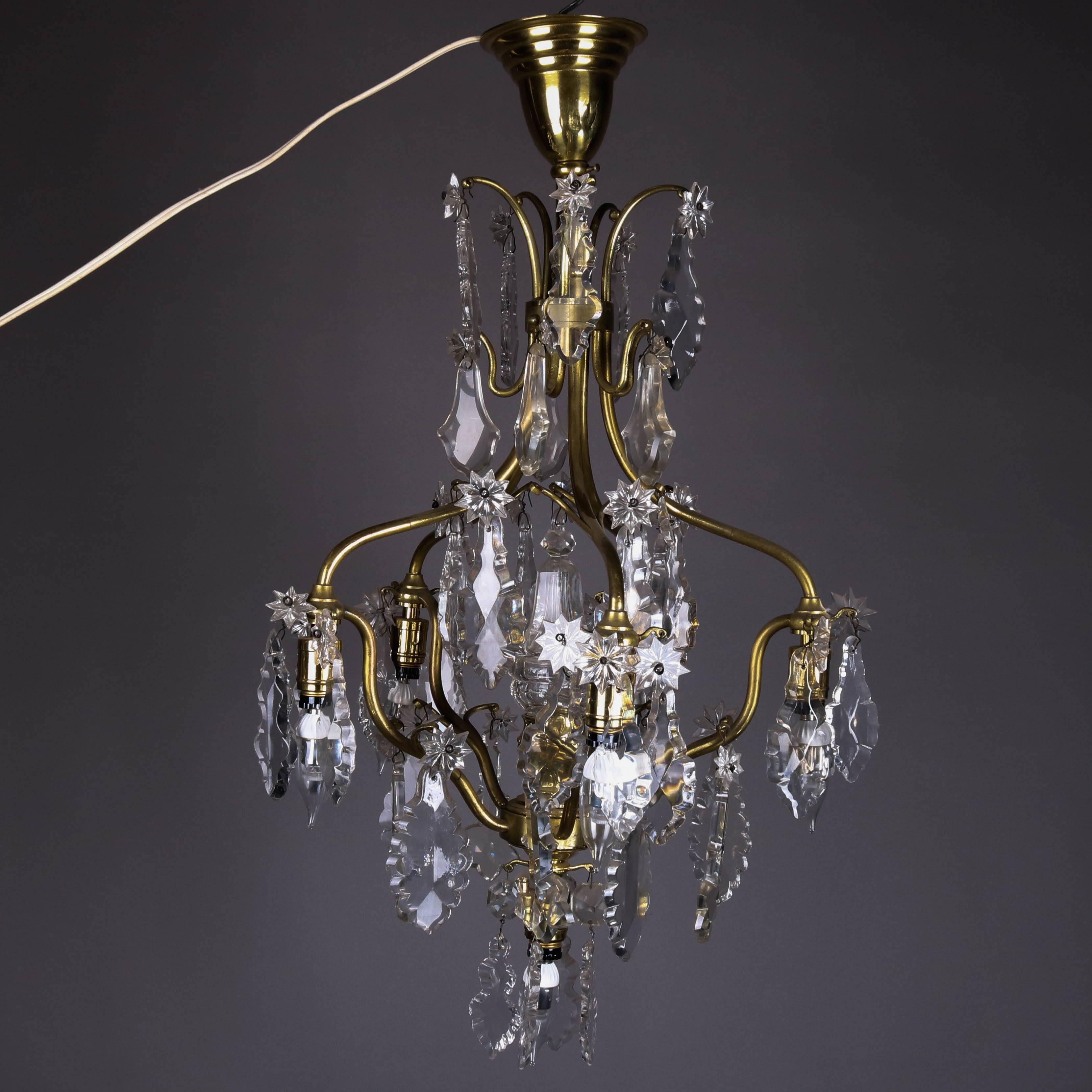 French five-light chandelier features curvilinear brass frame decorated with stylized flower and leaf form cut crystal prisms, 20th century

Measures: 32