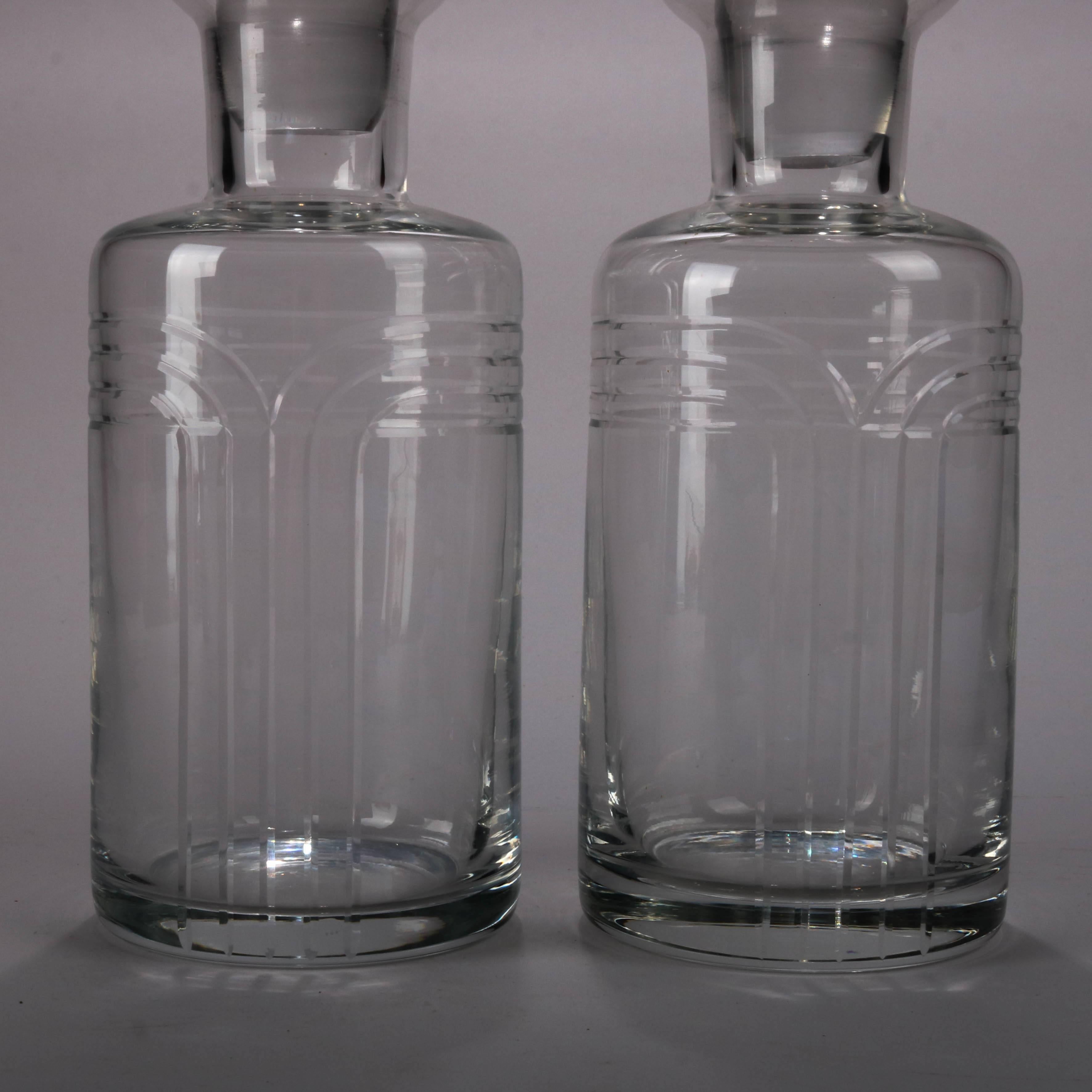 Pair of vintage French Baccarat School crystal decanters feature embossed geometric design and matching stoppers, 20th century

Measure: 12" height x 4" diameter.
