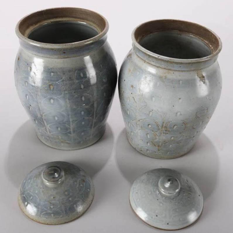 Pair of Mid-Century Modern hand-thrown studio art pottery lidded jars or canisters feature milky blue glaze over incised repeating design of linear pattern concentric circles, singed "H" on base, mid-20th century
Provenance: Deaccessioned