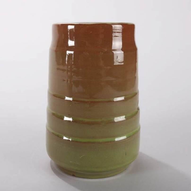 Mid-Century Modern hand-thrown vessel features avocado green and chocolate glazing with high gloss finish, banded cylindrical form with footed base, signed, mid-20th century
Provenance: Deaccessioned from the Randy Webb Collection of the Call Museum