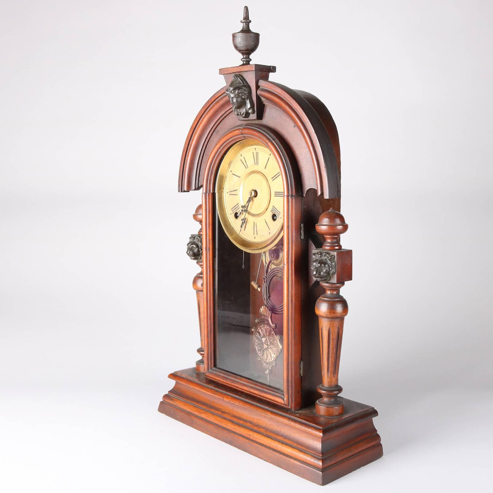 Antique figural mantel clock by Ingraham Mascot features arched form crest with central female mask and finial, flanking column supports with carved lion heads, key included, original label within, circa 1879

Measures: 24