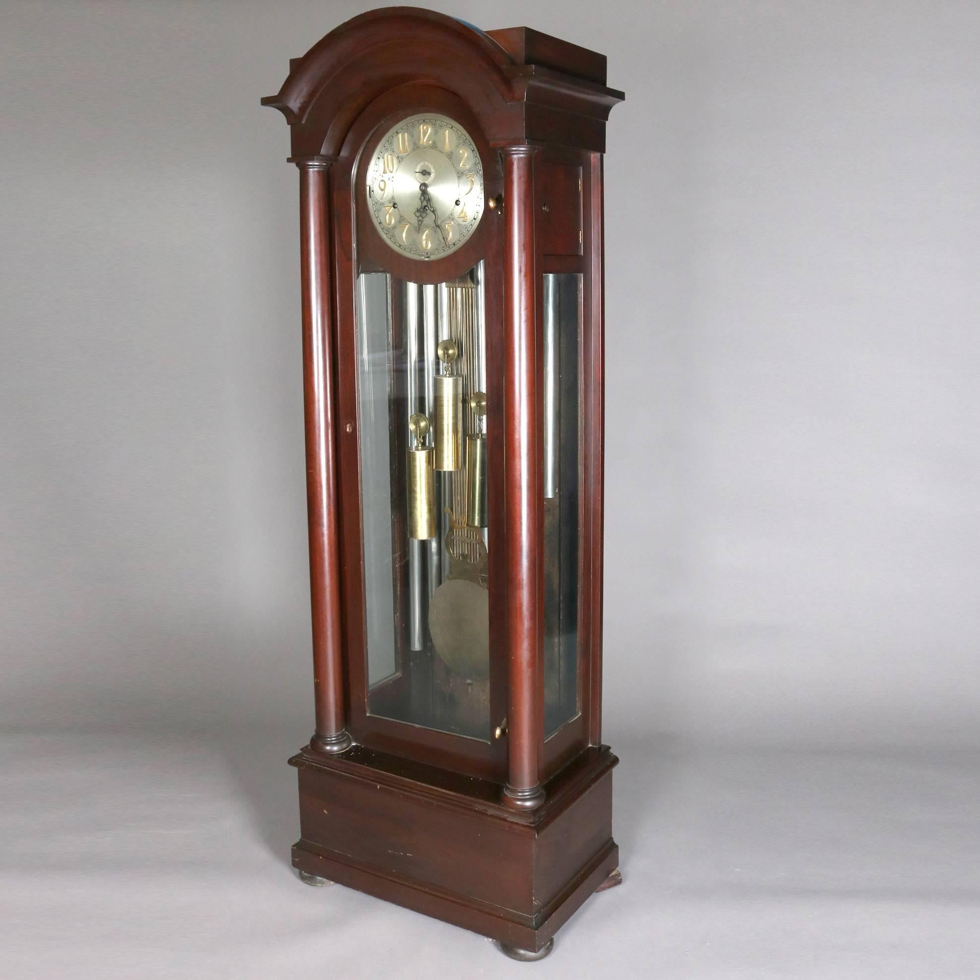 Antique American Empire grandfather clock by Jacques features arched mahogany case with column supports with glass sides and front, signed on face bottom centre, 19th century

Measures - 76" H x 27" W x 16" D.