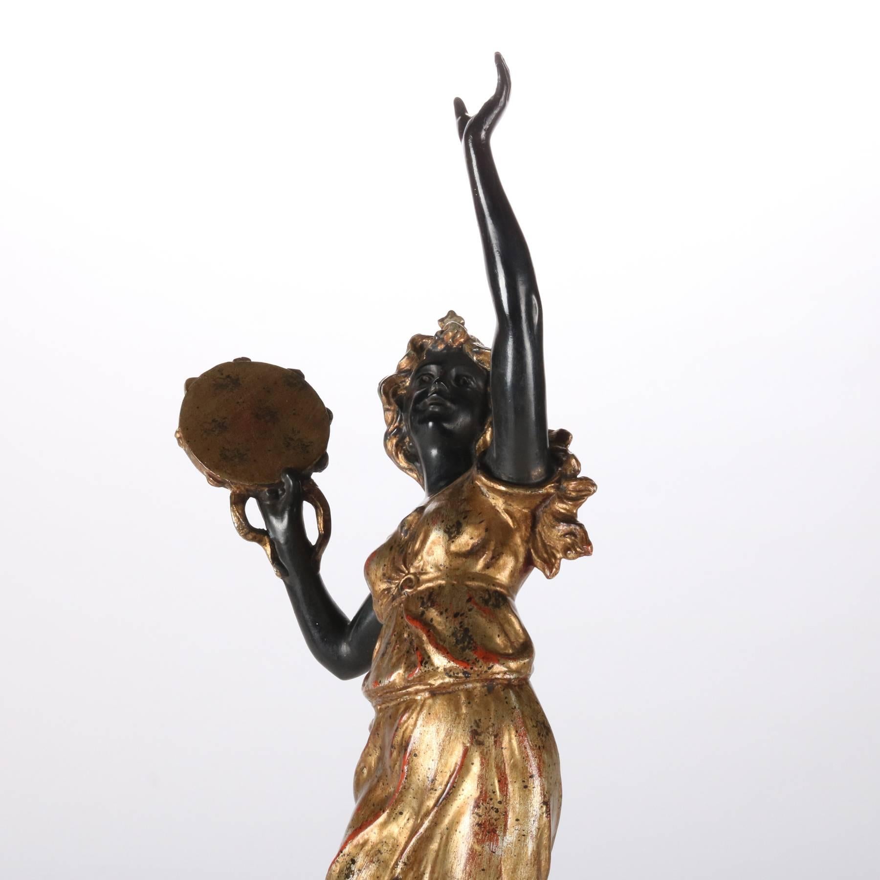 Parcel-gilt and ebonized metal sculpture of muse dancing and playing tympanum, 20th century.

 