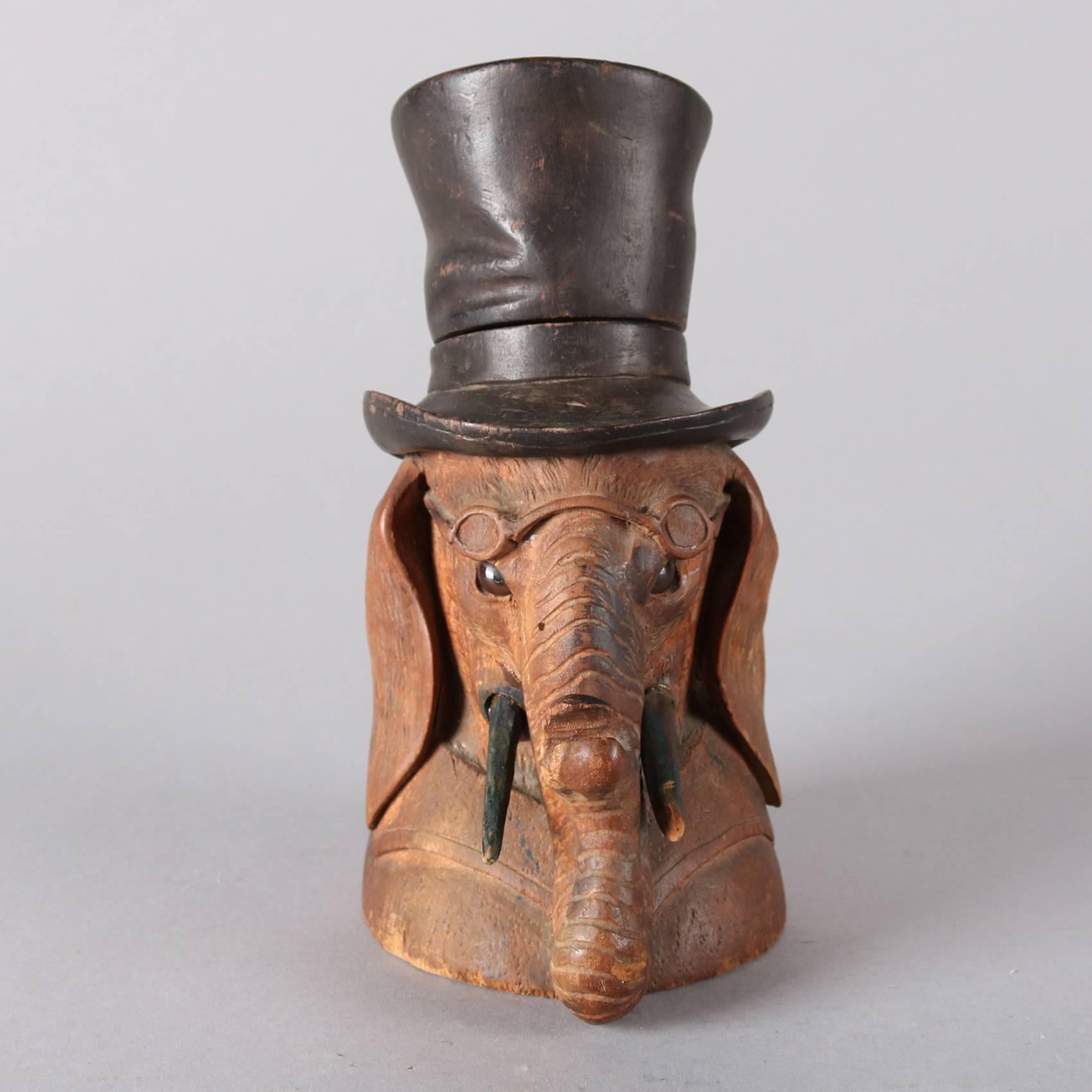 Antique German Black Forest figural ink well features hand-carved elephant with top hat and spectacles; ebonized hat, tusks and eyes; top hat opens to copper well inset, 19th century.

Measures: 7.5