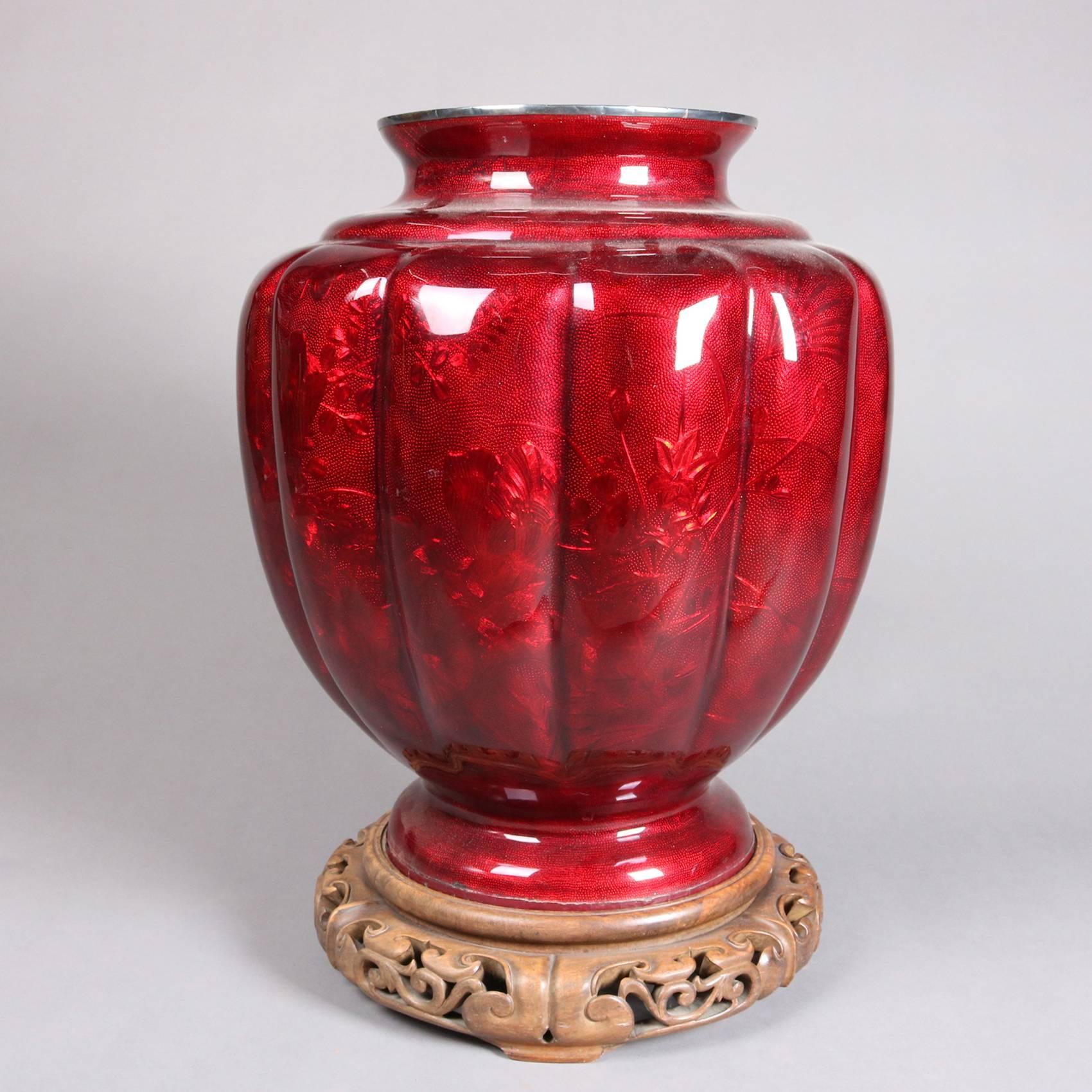 Antique monumental Meiji period Ginbari urn form floor vase features pigeon blood red cloisonne enamel and embossed foliate and stippled foil, silvered rim, seated on carved and pierced base, 20th century

Measures: 27