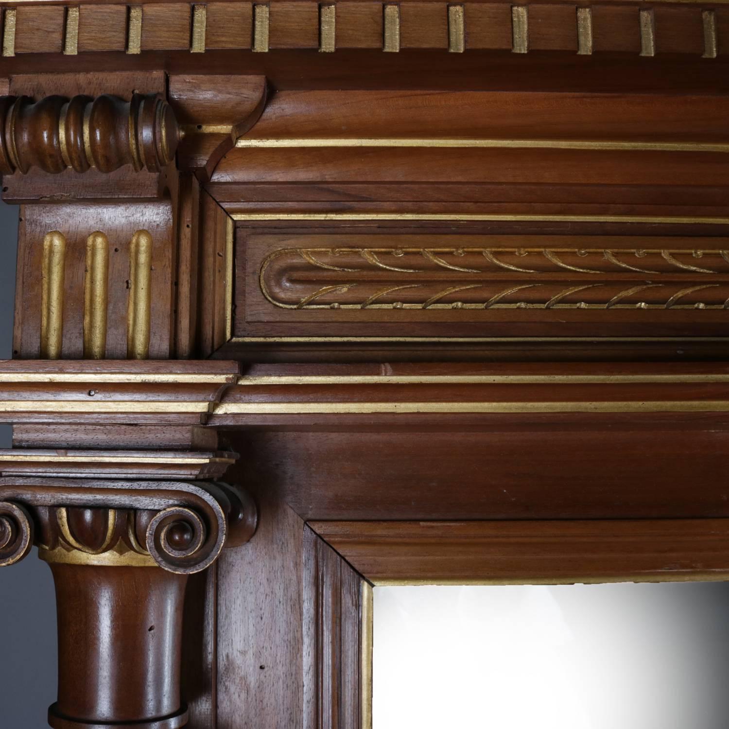 Neoclassical pier mirror features mahogany construction; gilt decorated carving including crest with dental molding, foliate motif, and flanking Corinthian columns; mirrored upper supported by marble top base with lower display, also flanked by