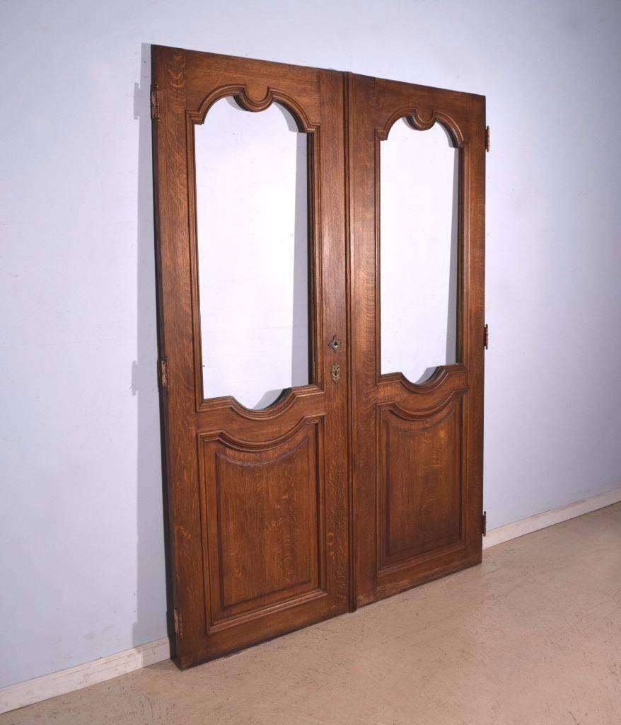 This solid oak door set (two doors) is from France and dates to the early to mid-1900s. These doors originally had stained glass windows but the glass is missing and can be replaced with glass of your choice. These are exterior doors and they are in