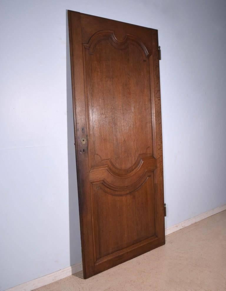This elegant antique door is from France and it dates to the late 1700s or early 1800s. All of the woodwork is hand carved from solid oak and finished to a warm medium oak color. This was an interior door and therefore shows no weather damage.