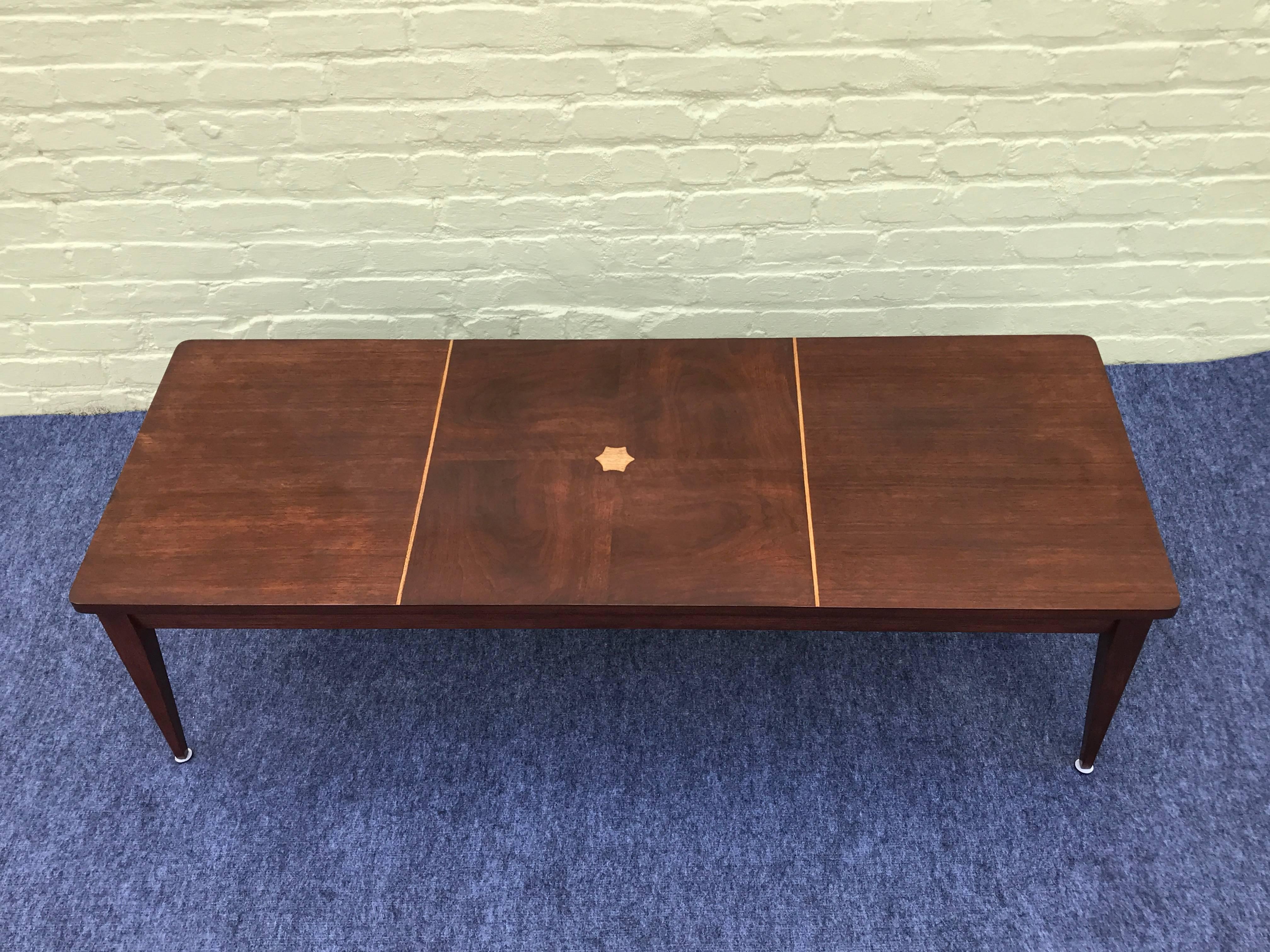 Offered is a gorgeous, 1960s dark walnut coffee table with blonde wood inlay. Marked: Mersman.