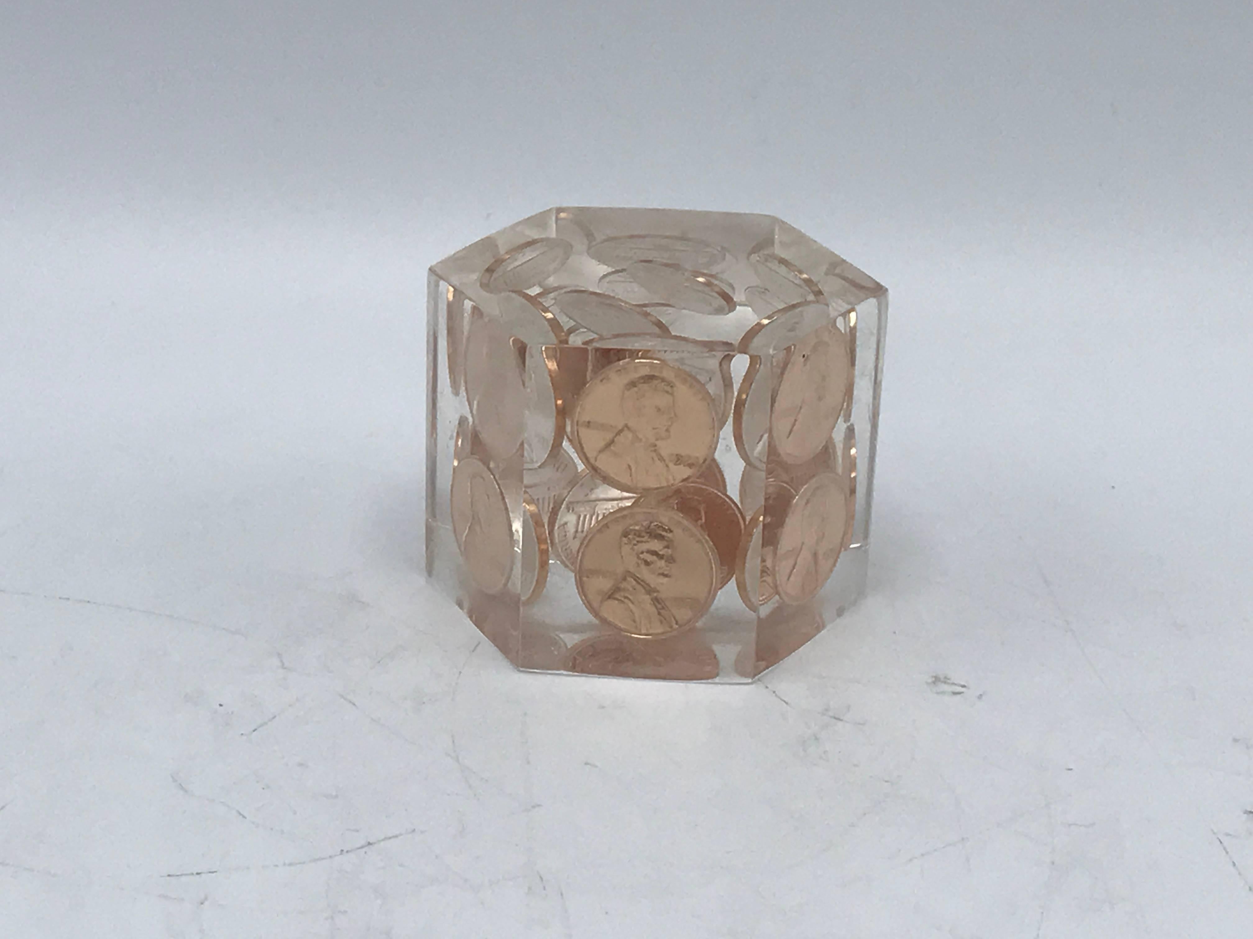 Offered is a 1980s pop-art Lucite paperweight with several US copper pennies encased within the Lucite. Hexagon shape.