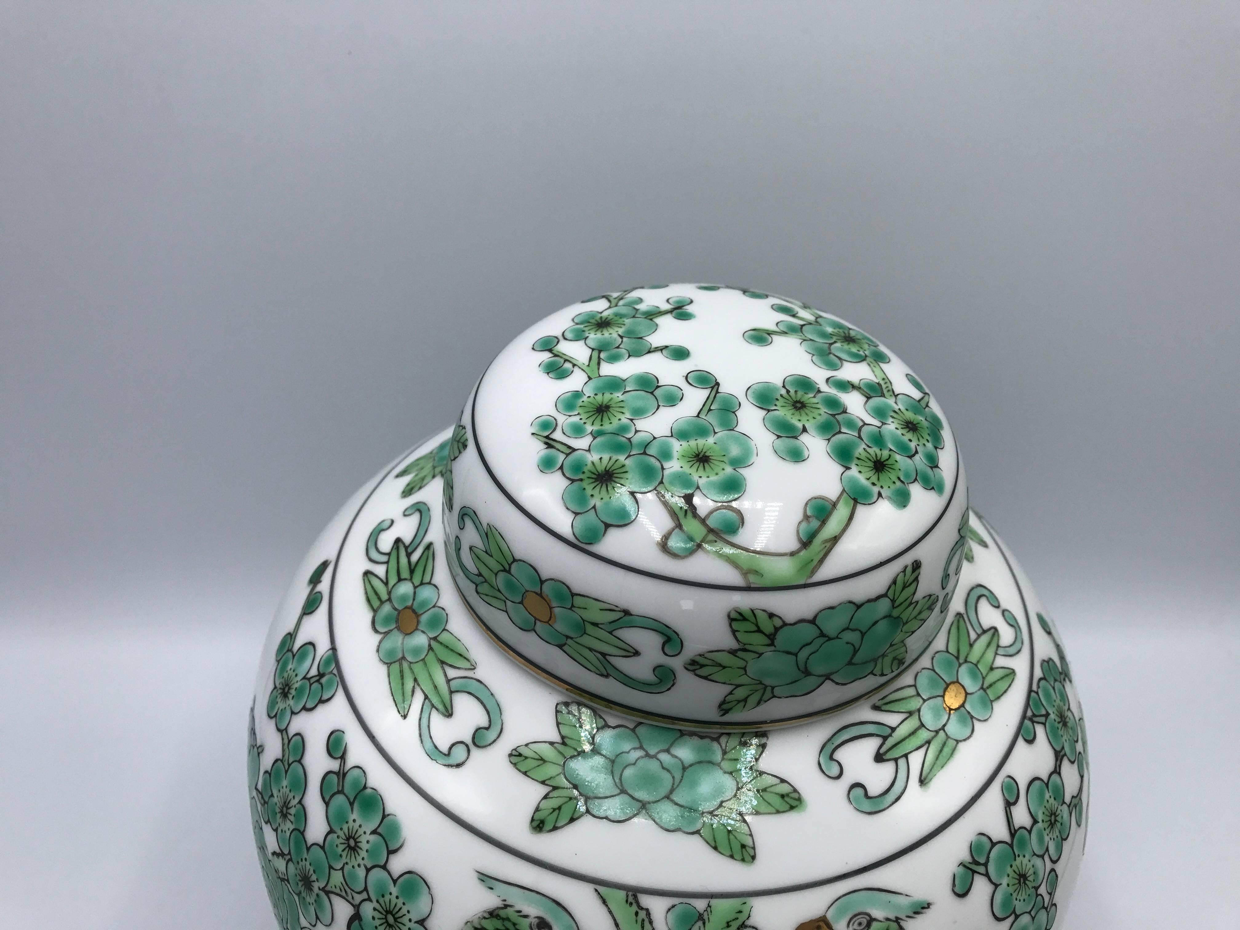 Offered is a gorgeous, 1960s gold Imari ginger jar with a green, white, and gold peacock motif. Ginger jar rests on a decorative wood stand. Marked on underside.