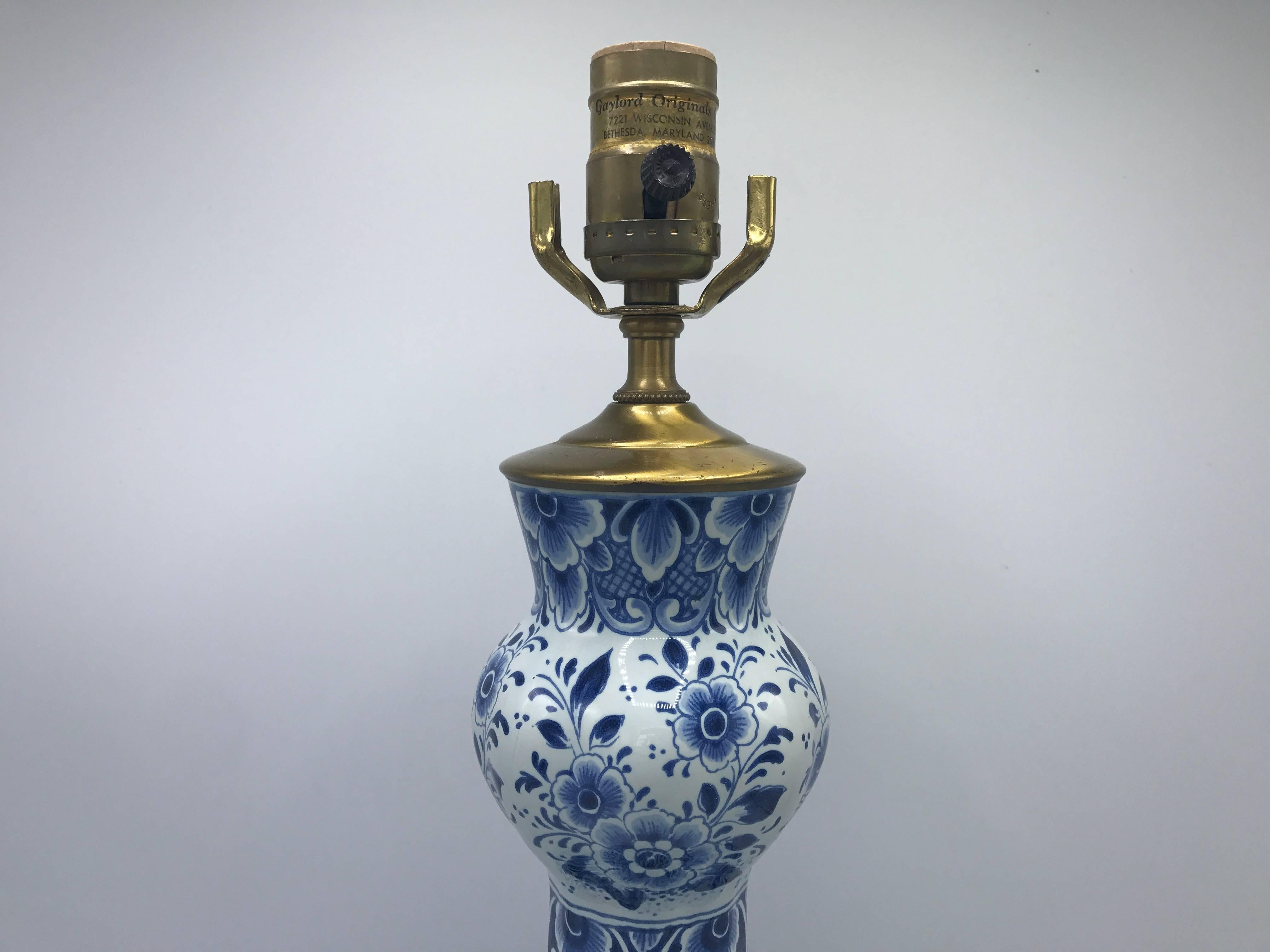 Offered is an exquisite, 19th century blue and white delft vase converted to a lamp with an all-around floral motif. Rested on a brushed brass base. New socket, wiring, and base.