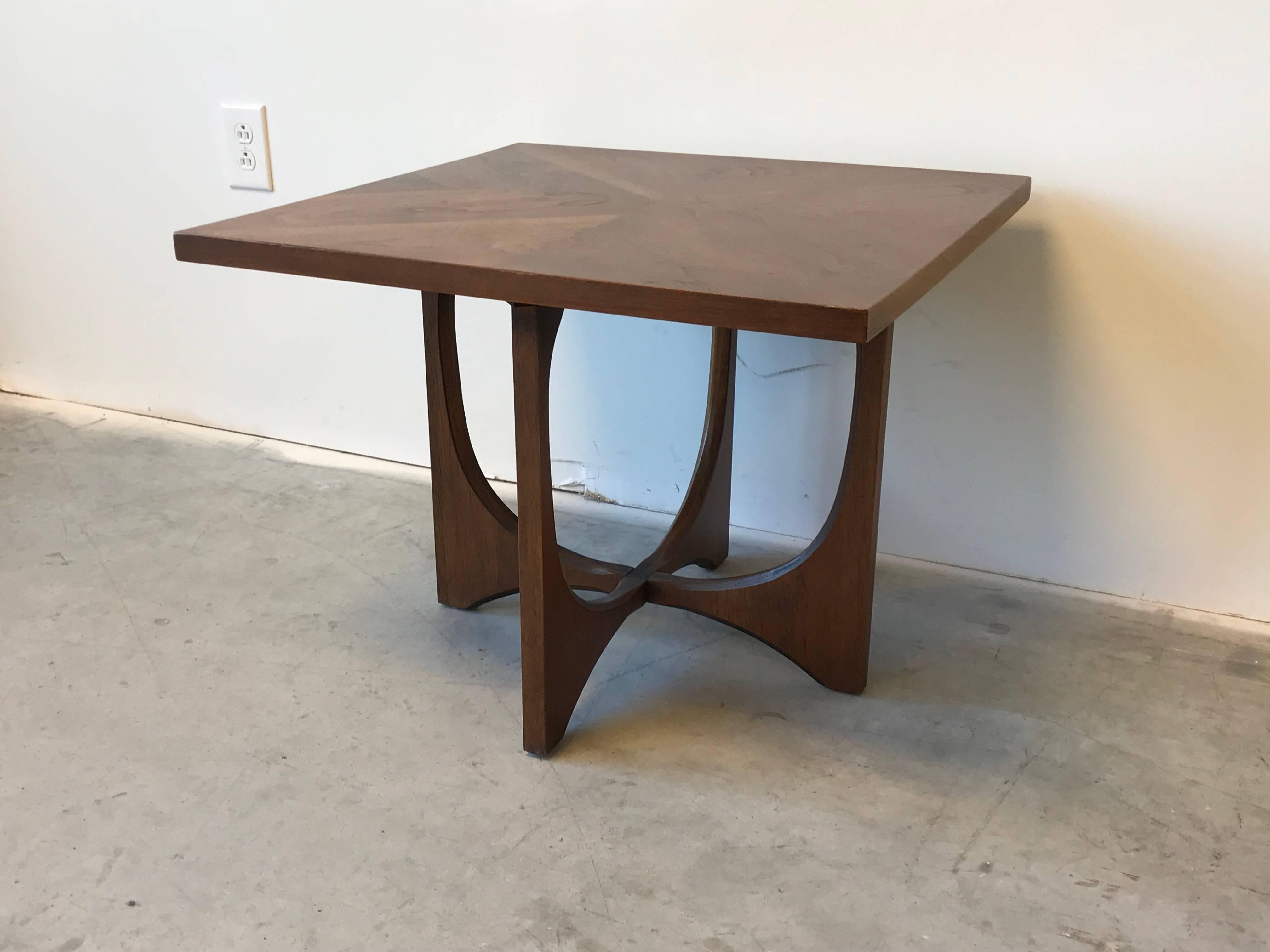 Offered is a stunning, 1960s Broyhill Brasilia walnut side table. Introduced by Broyhill in the 1960s, the Brasilia collections signature lines and waves were inspired by the distinct architecture of the city of Brasilia, the capital of Brazil.
    