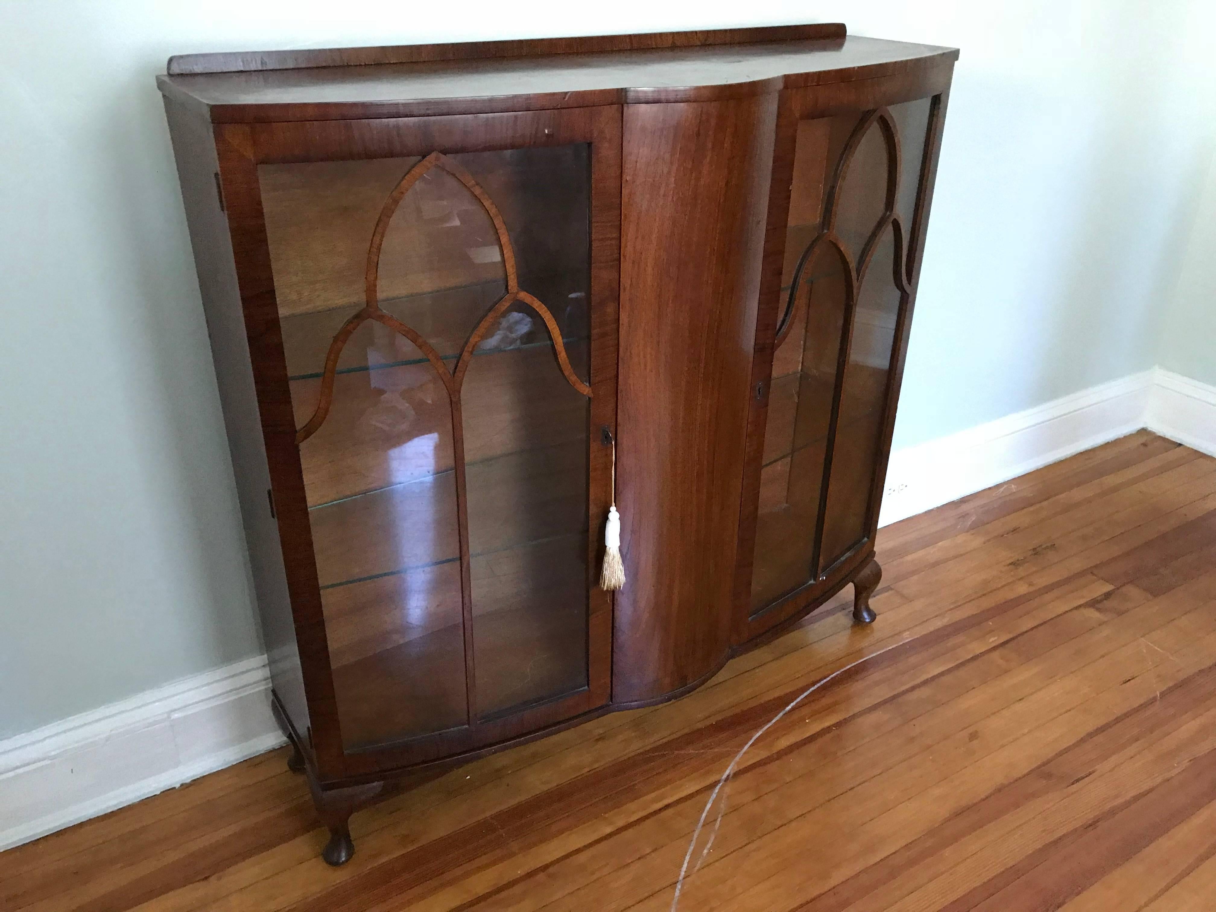 Offered is a beautiful, 1920s French Art Deco walnut and glass curio display cabinet. The piece has two doors, three shelves, and includes the original key.